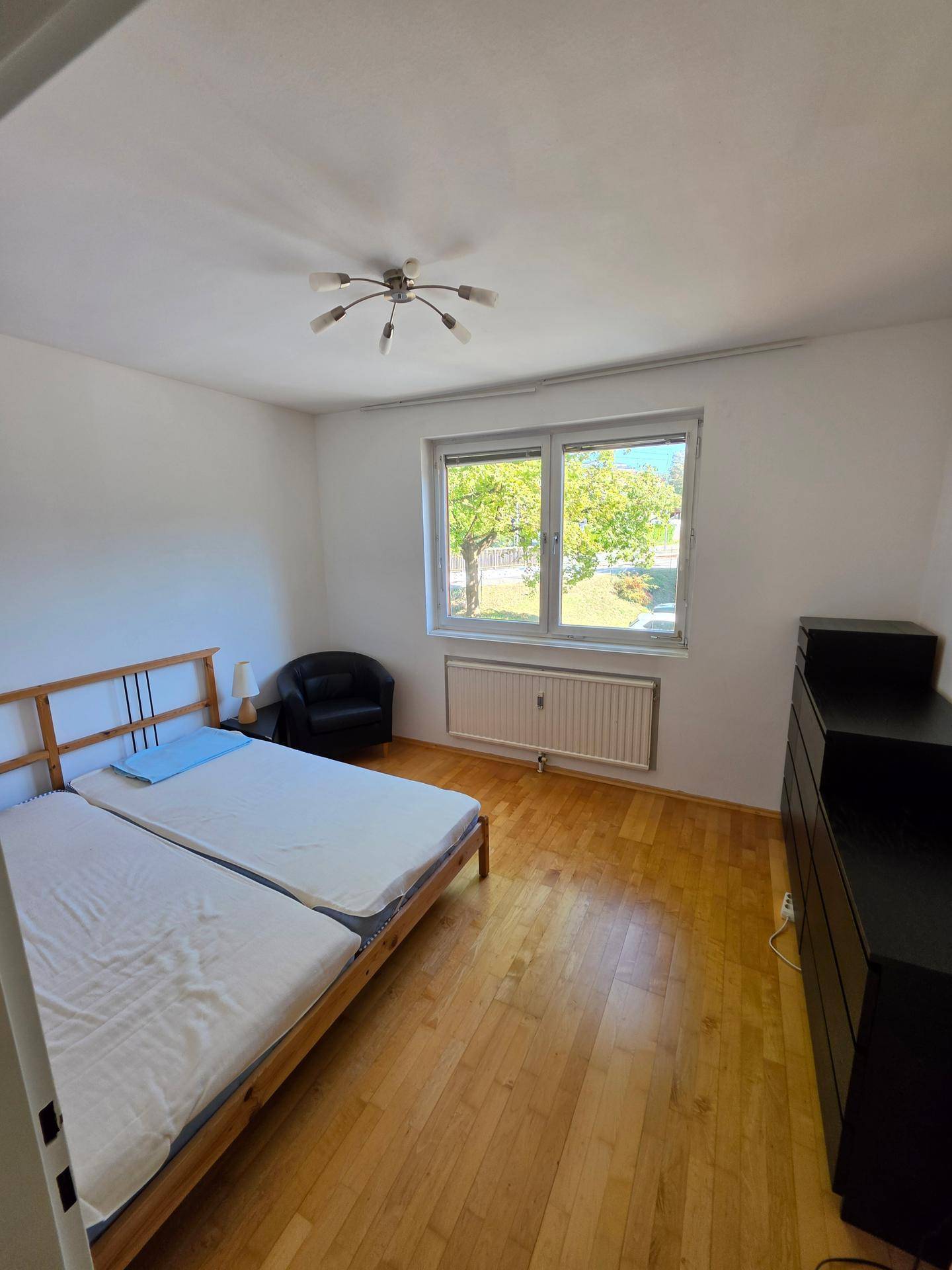 Helles Schlafzimmer mit zwei Einzelbetten, Holzfußboden und Blick ins Grüne.