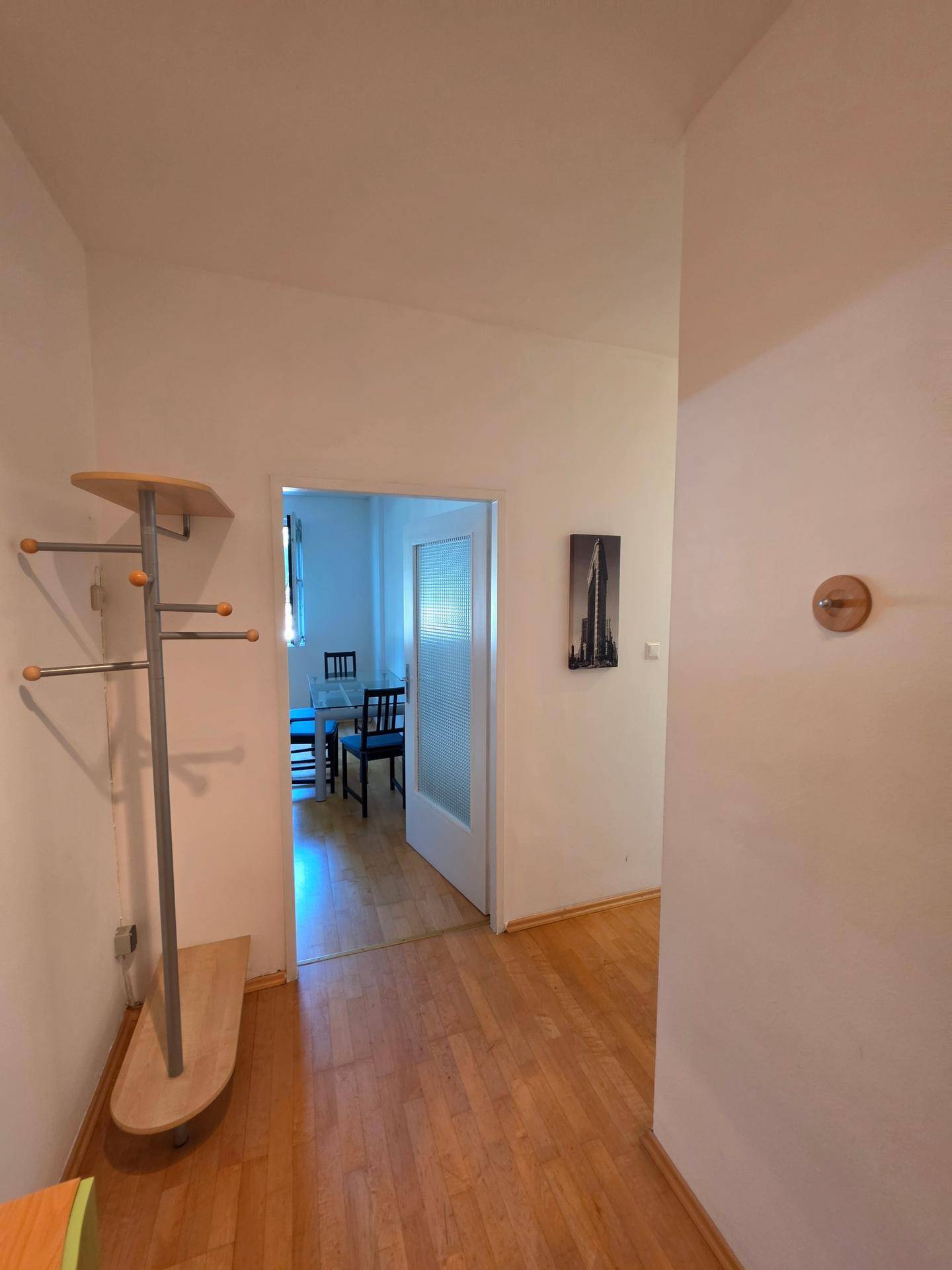 Eingangsbereich mit Garderobe und Holzfußboden, der zu weiteren Räumen führt.