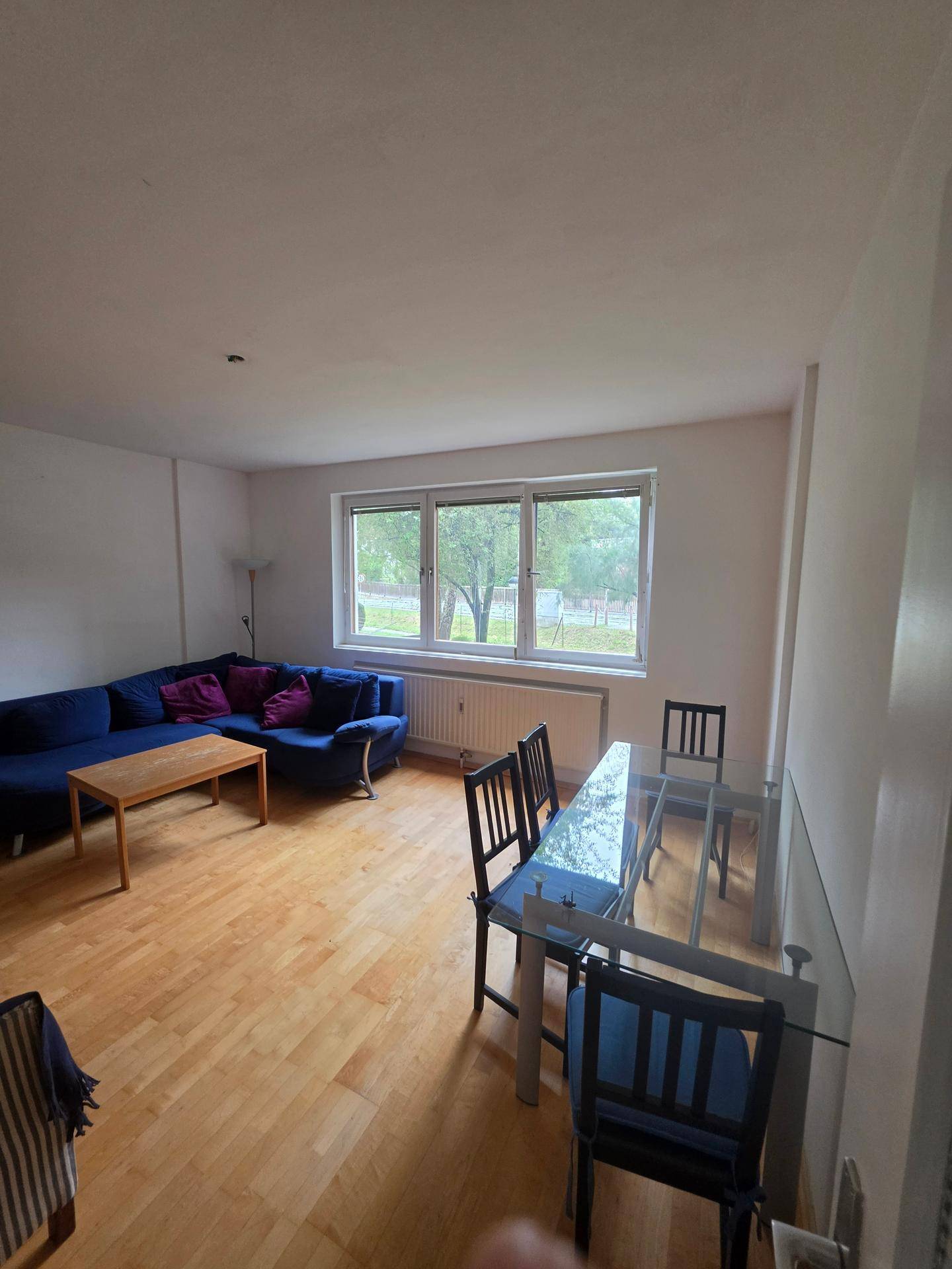 Geräumiger Wohn-Essbereich mit Sofa, Esstisch und großen Fenstern.