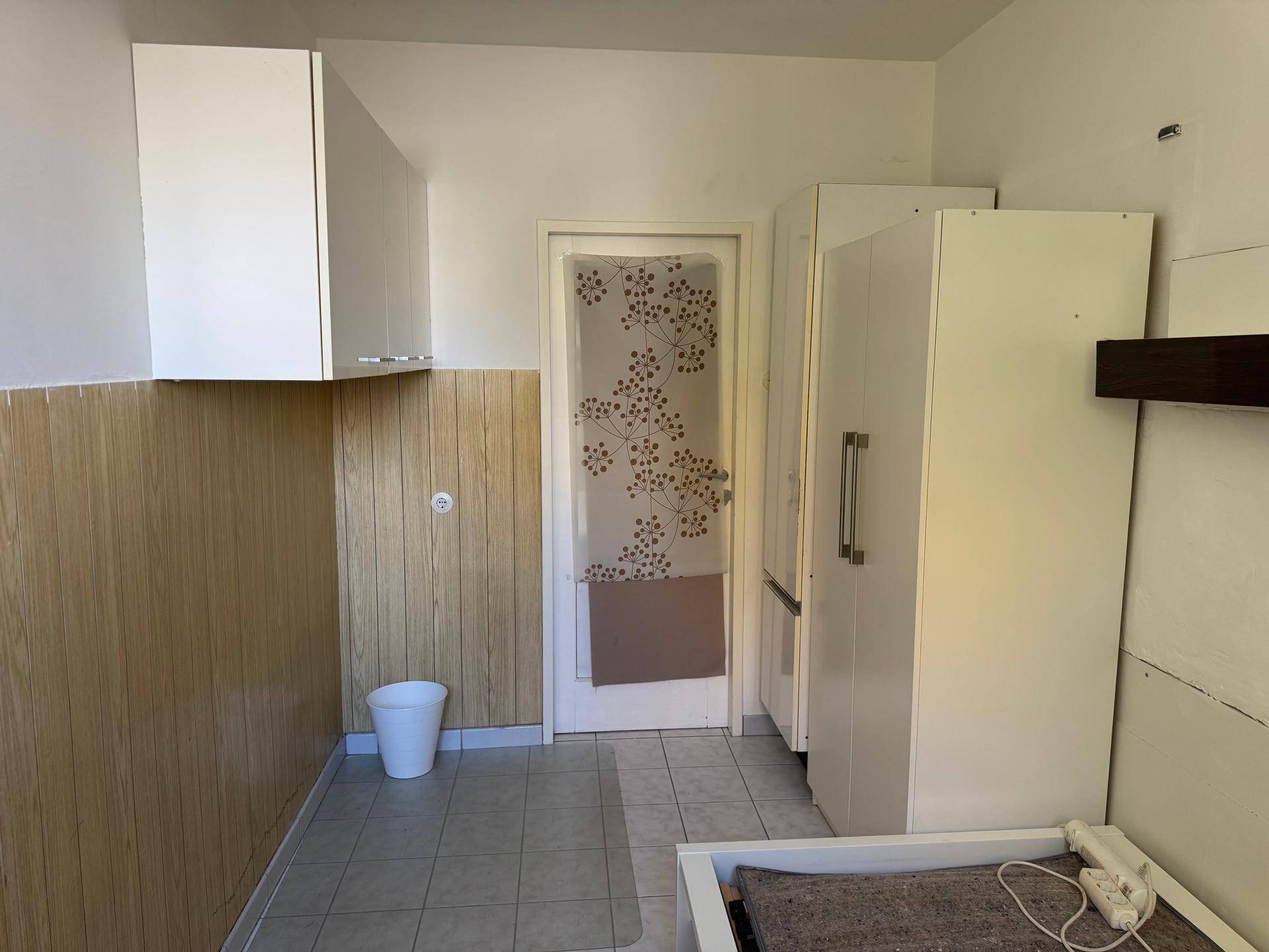 Weiterer Blick in das kleine Schlafzimmer mit Fliesenboden und weißen Schränken.