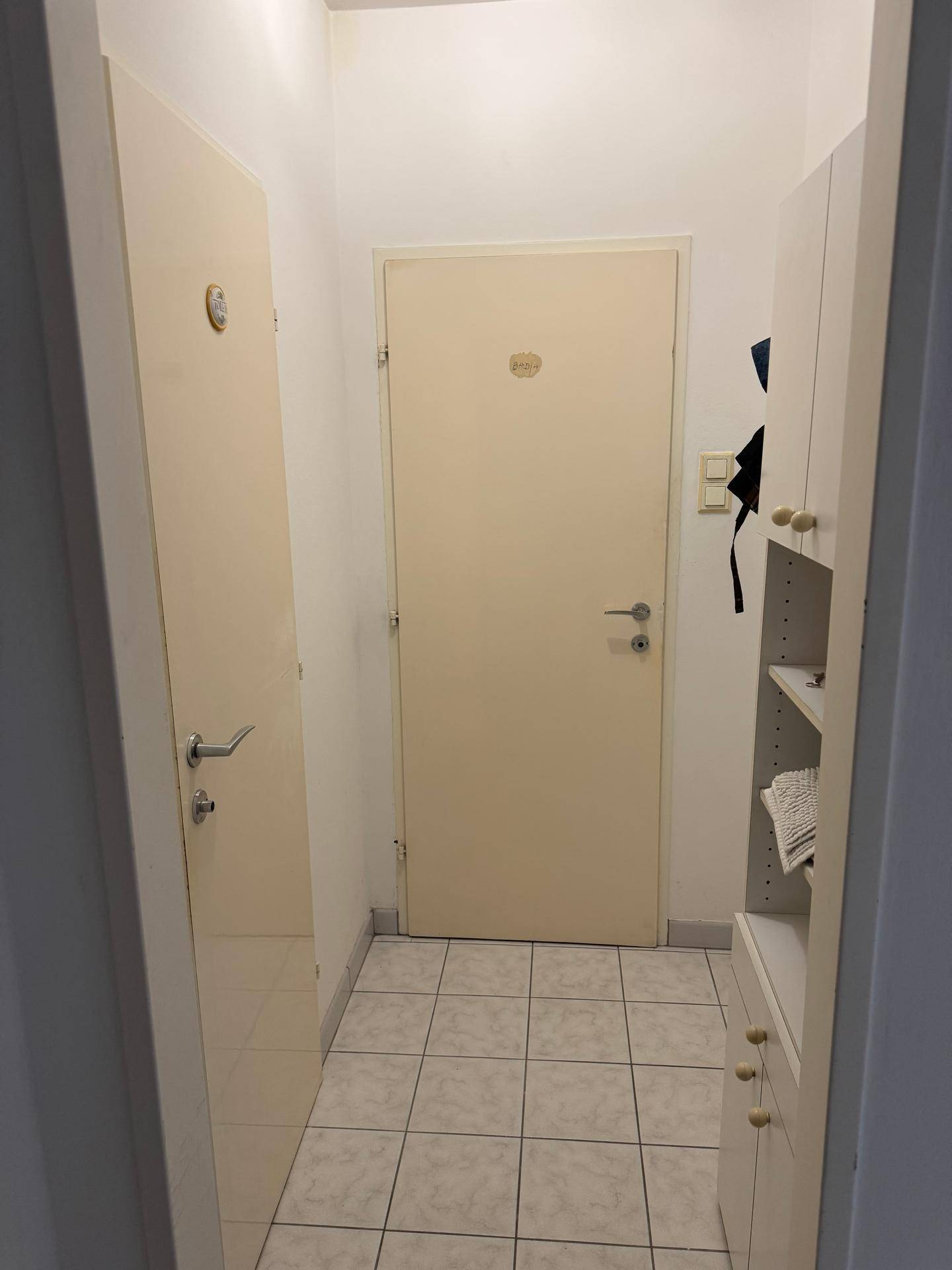 Kleiner Eingangsbereich mit Fliesenboden und praktischen Einbauschränken.