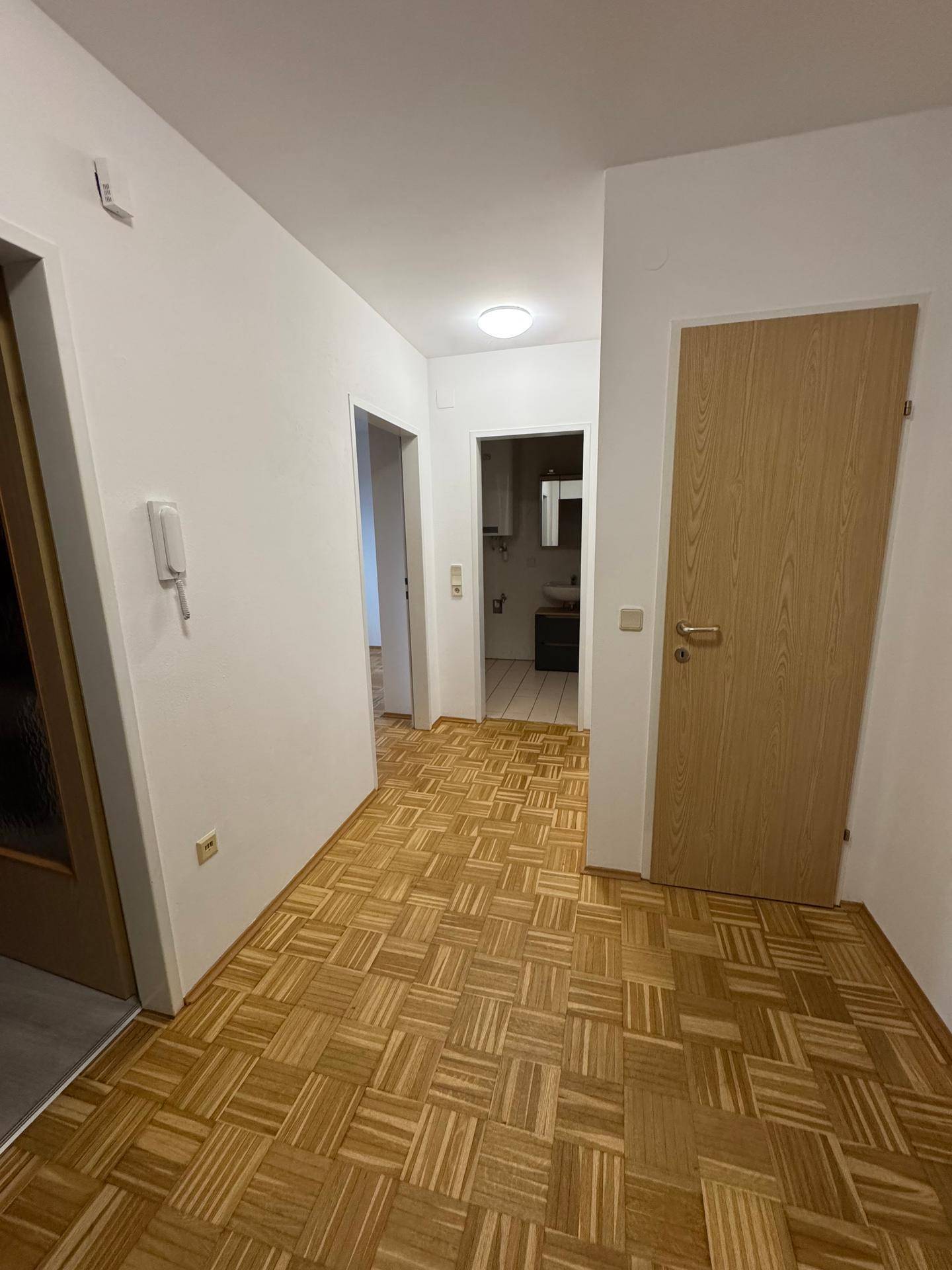 Heller Flur mit Parkettboden, der den Zugang zum Badezimmer und weiteren Räumen ermöglicht.