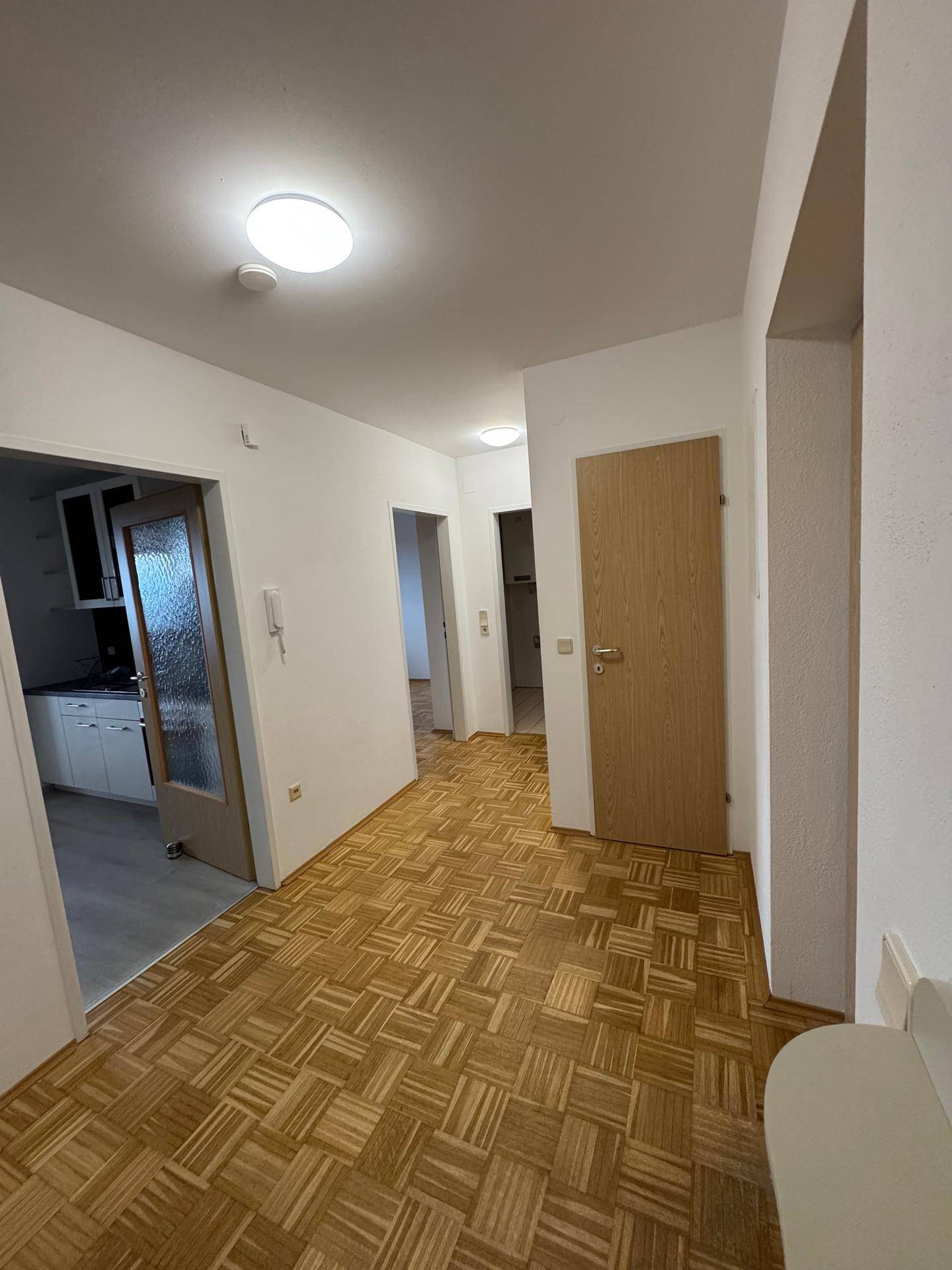 Geräumiger Flur mit hellem Parkettboden und mehreren Türen zu den angrenzenden Räumen.