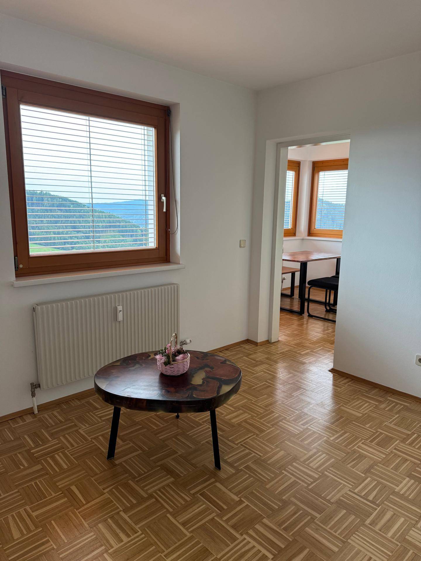 Lichtdurchflutetes Zimmer mit Parkettboden und weitem Blick über die umliegende Landschaft.