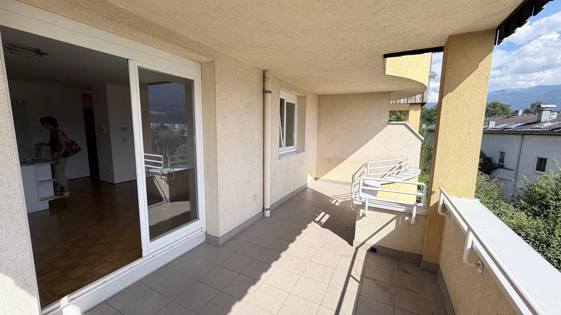 Langer Balkon mit Fliesenboden und Schiebetür zum Innenbereich, bietet einen weiten Blick.