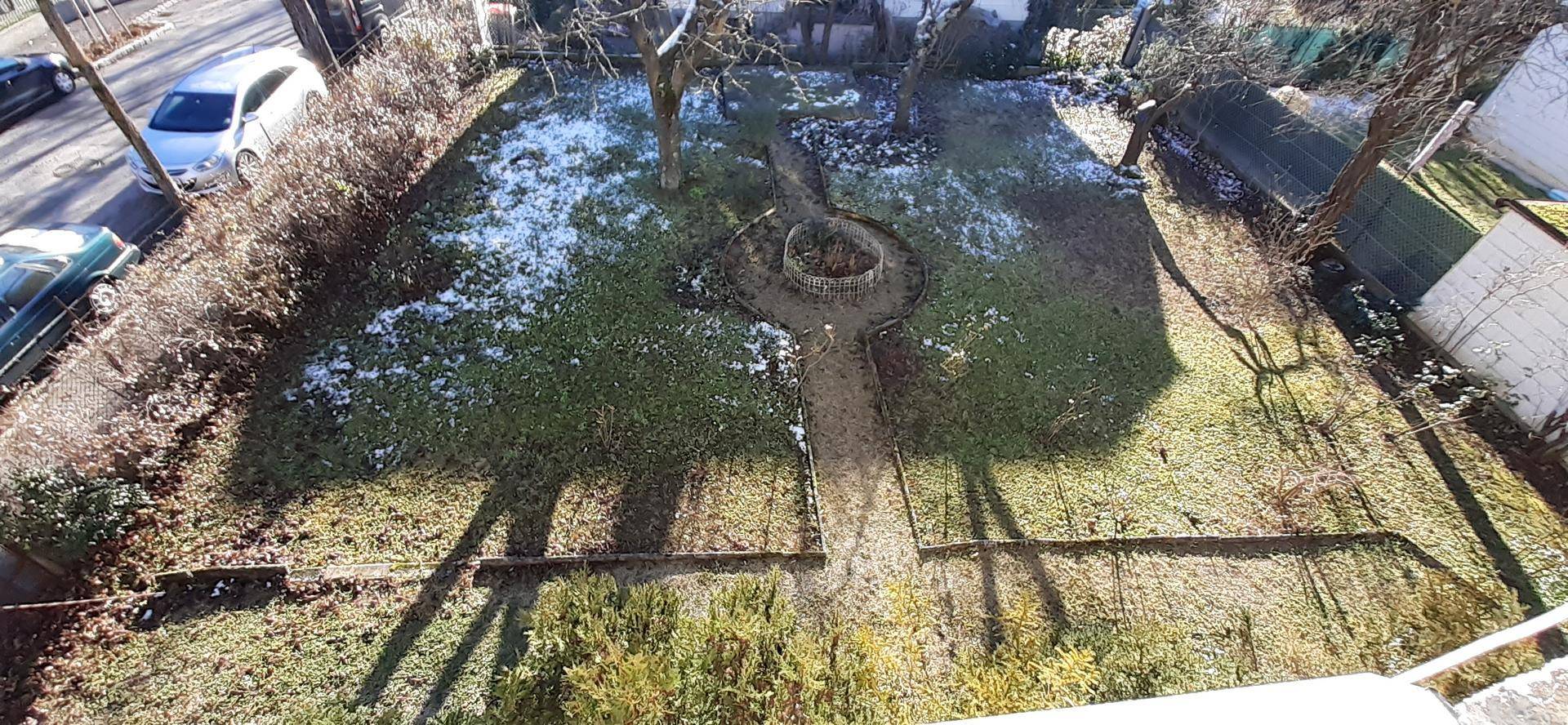 Gartenbereich von oben gesehen mit einem gewundenen Pfad und leichter Schneedecke im Winter.