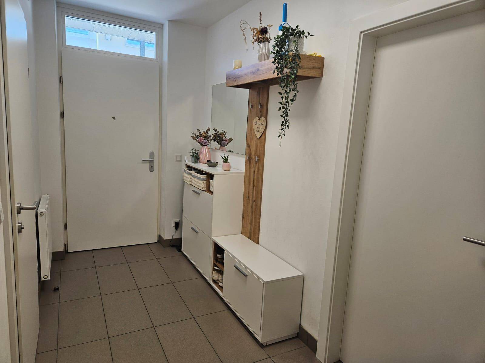 Heller Eingangsbereich mit Fliesenboden, Garderobe und praktischem Schuhschrank.