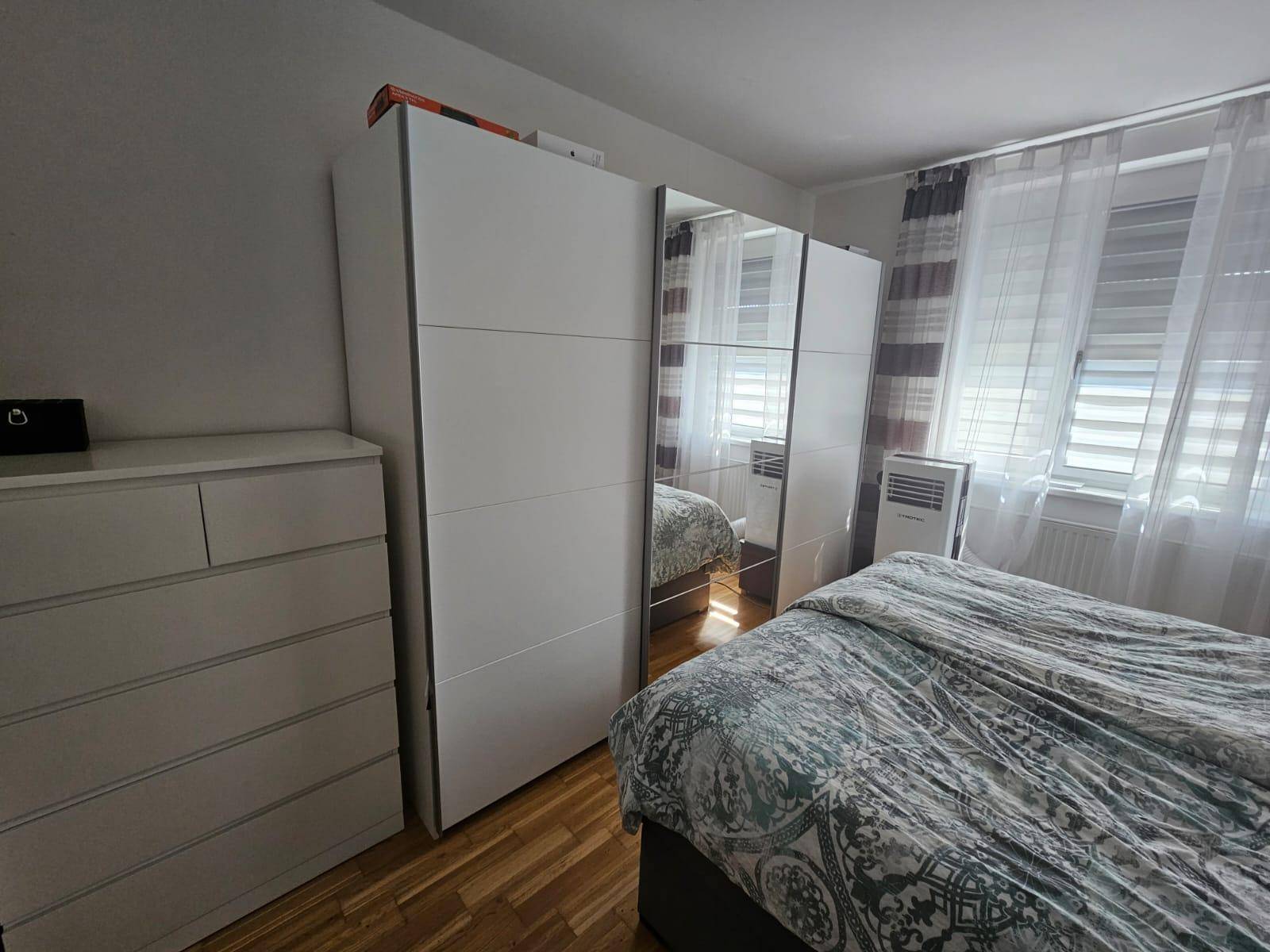 Schlafzimmer mit Kleiderschrank, Kommode und hellem Holzfußboden.