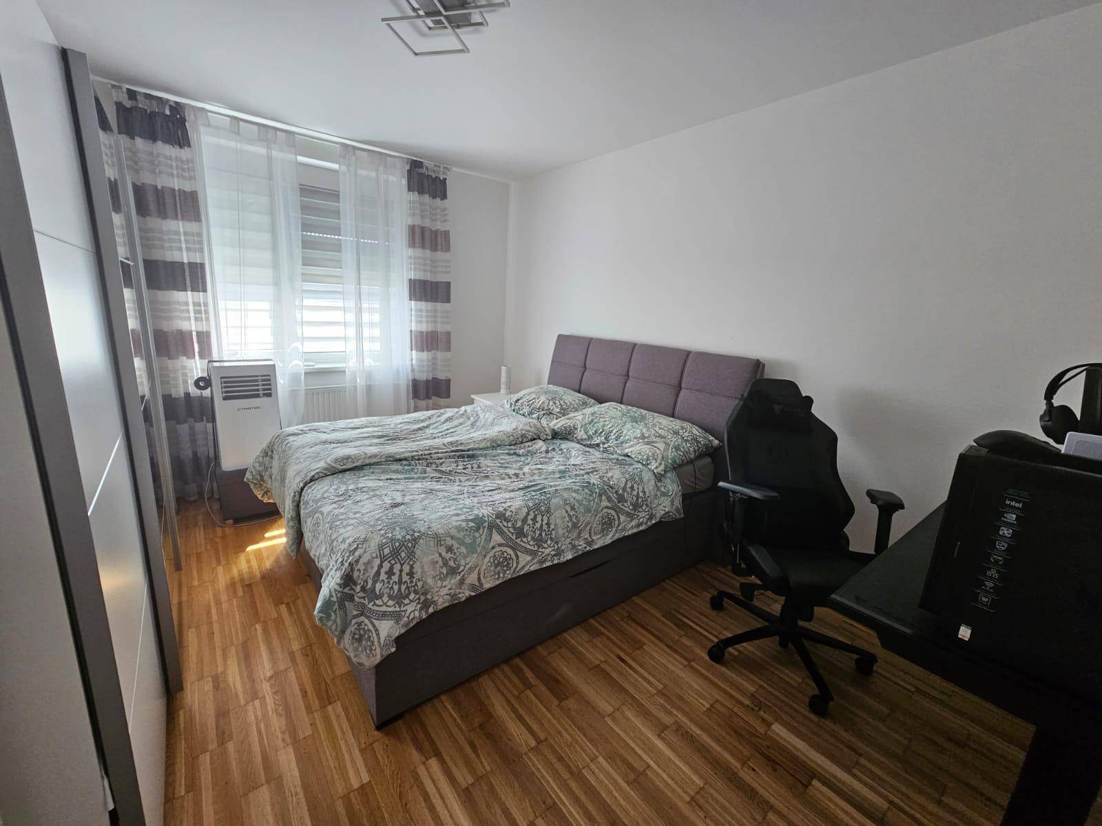 Gemütliches Schlafzimmer mit Doppelbett, Holzfußboden und großem Fenster für viel Licht.