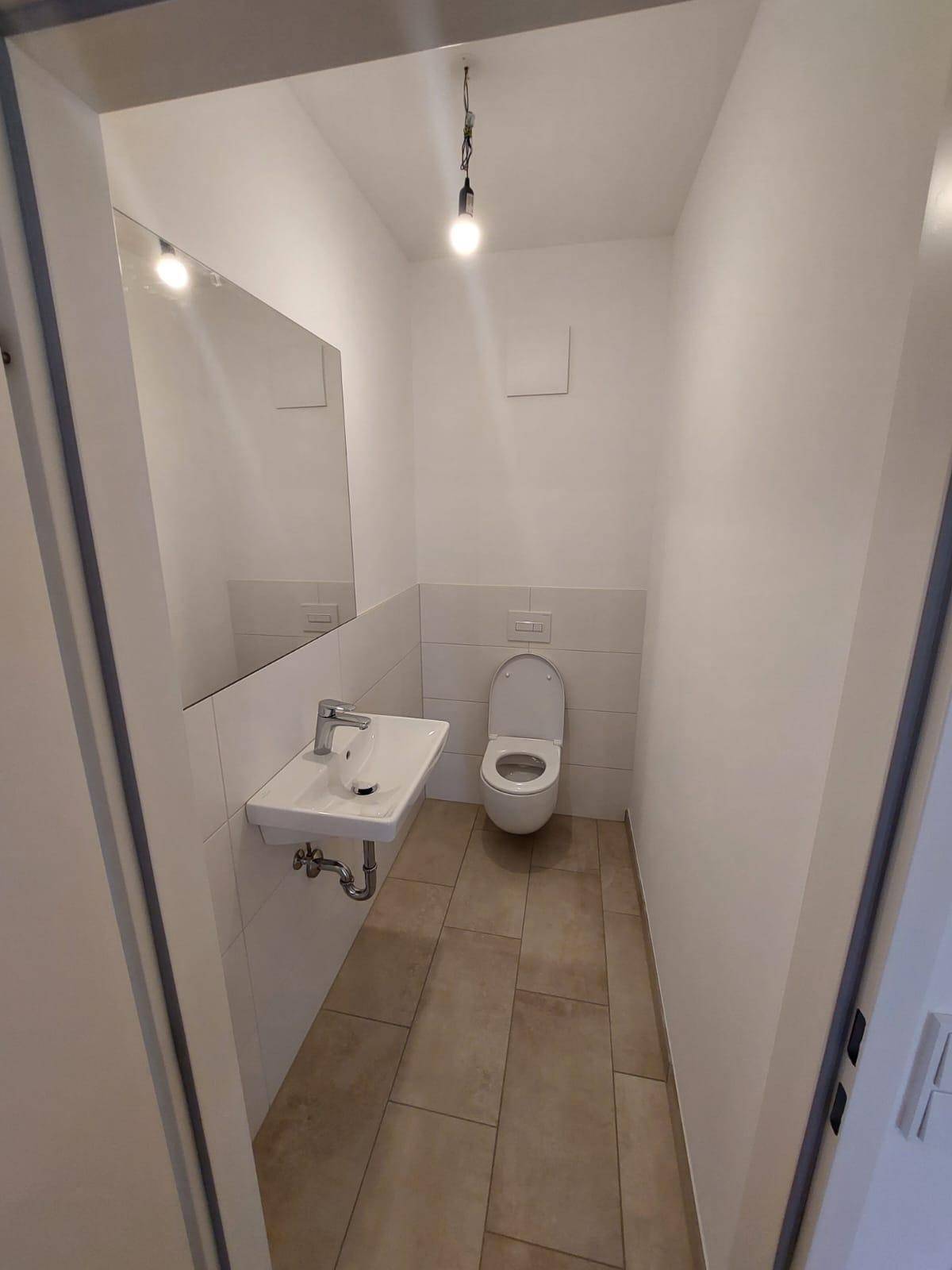 Gäste-WC mit wandhängender Toilette und einem einzelnen Waschbecken.