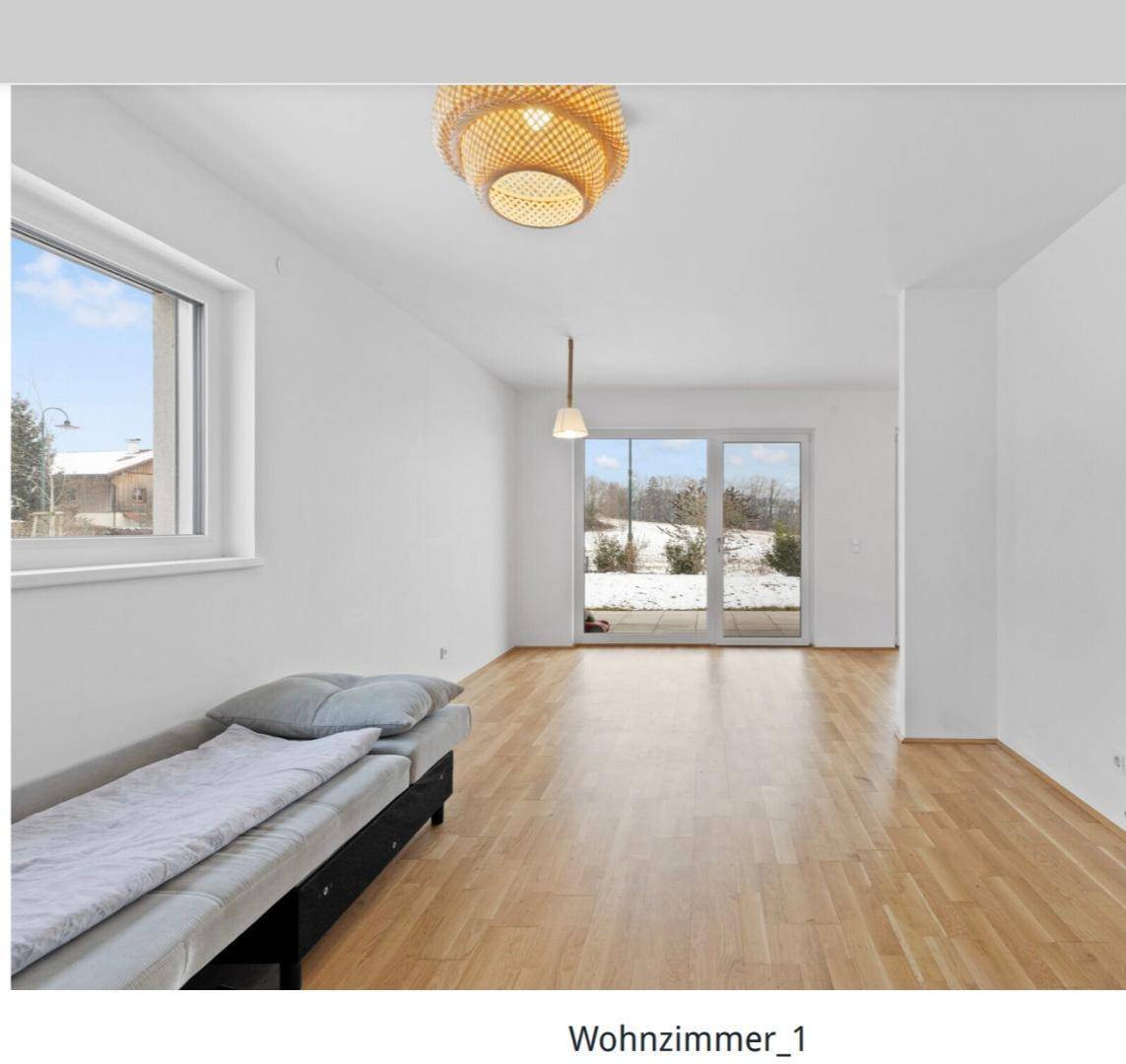 Helles Wohnzimmer mit Holzboden, großen Fenstern und Zugang zu einem Außenbereich mit Schnee.