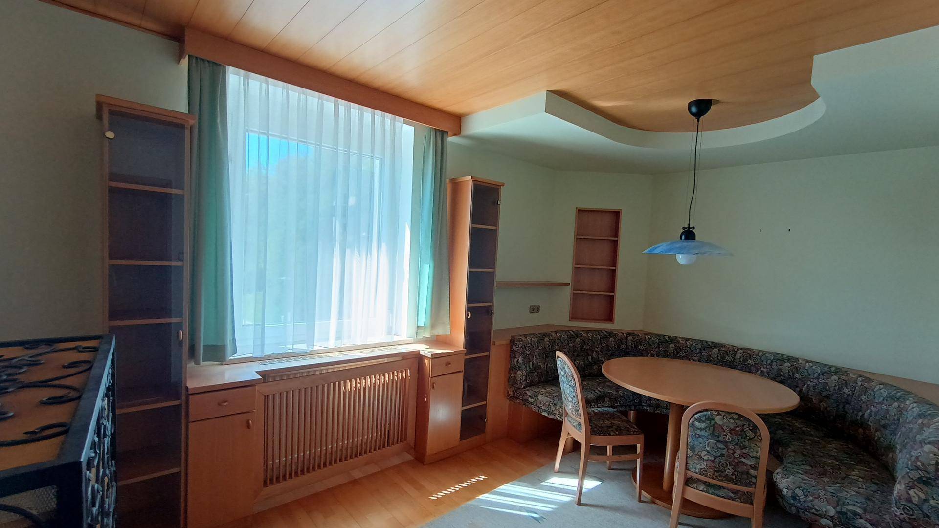 Gemütlicher Essbereich mit Holzelementen, Eckbank und großem Fenster.