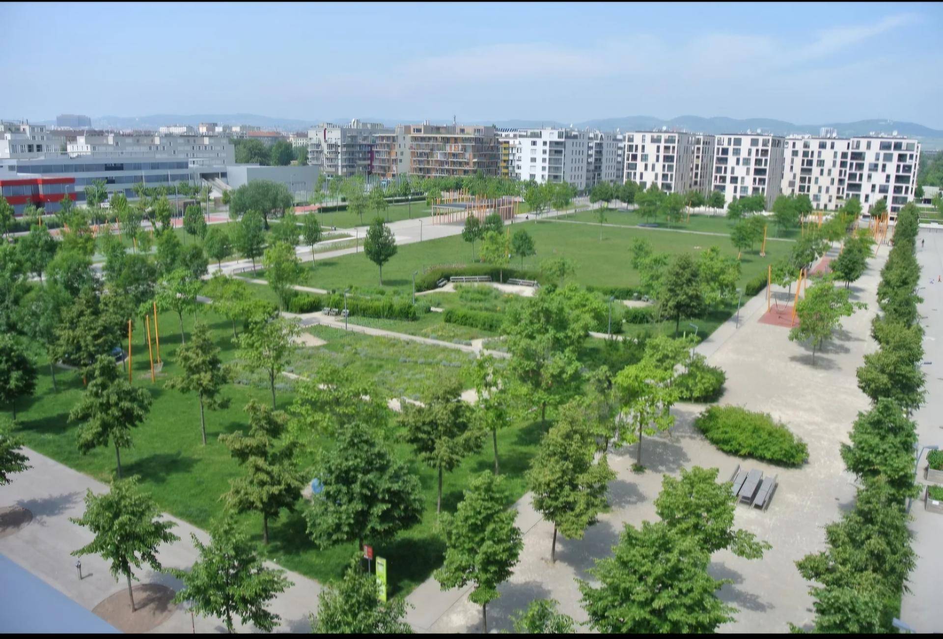 Weitläufige Grünflächen und moderne Wohngebäude in einer städtischen Umgebung.