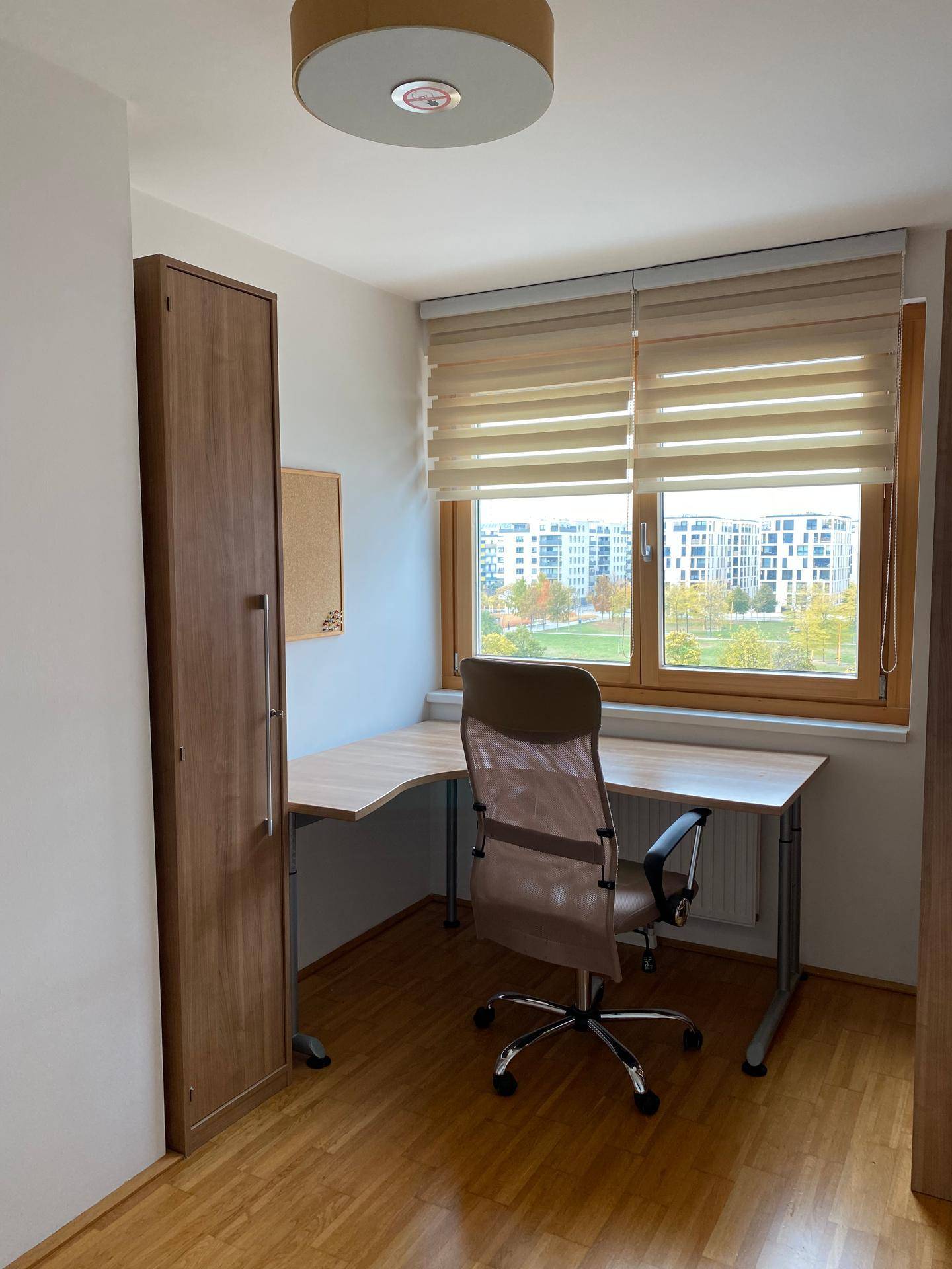 Helles Arbeitszimmer mit Holzboden, Schreibtisch und Blick auf die Stadt.