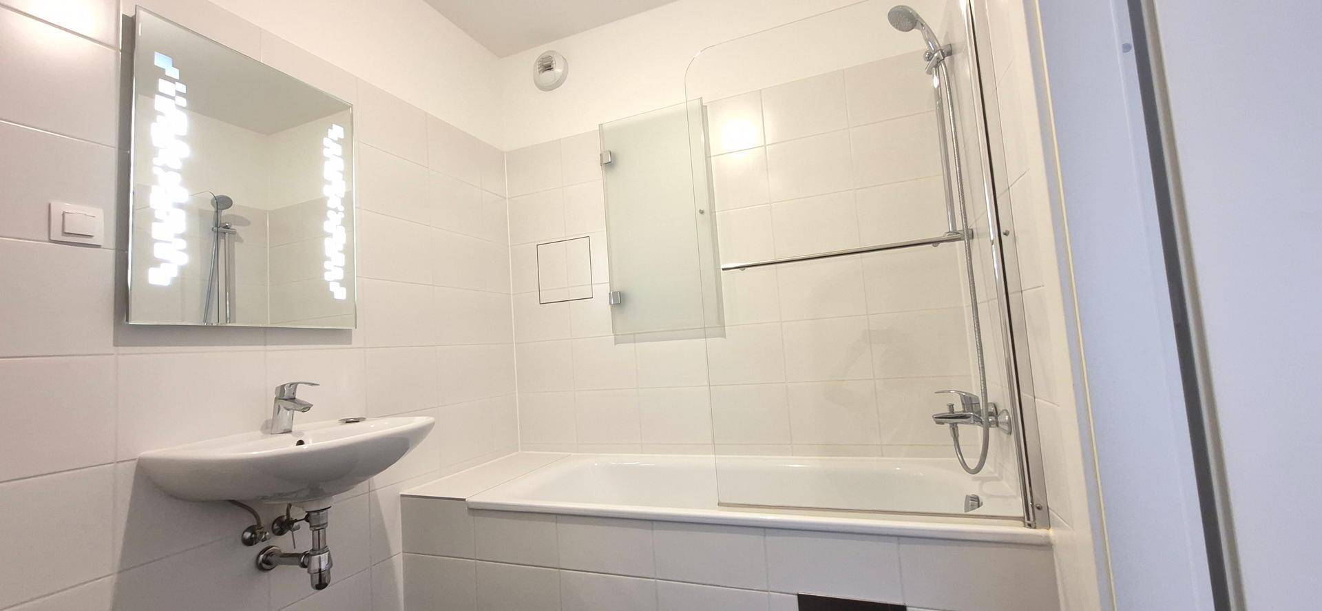 Modernes Badezimmer mit Badewanne, Duschvorrichtung und weiß gefliesten Wänden.