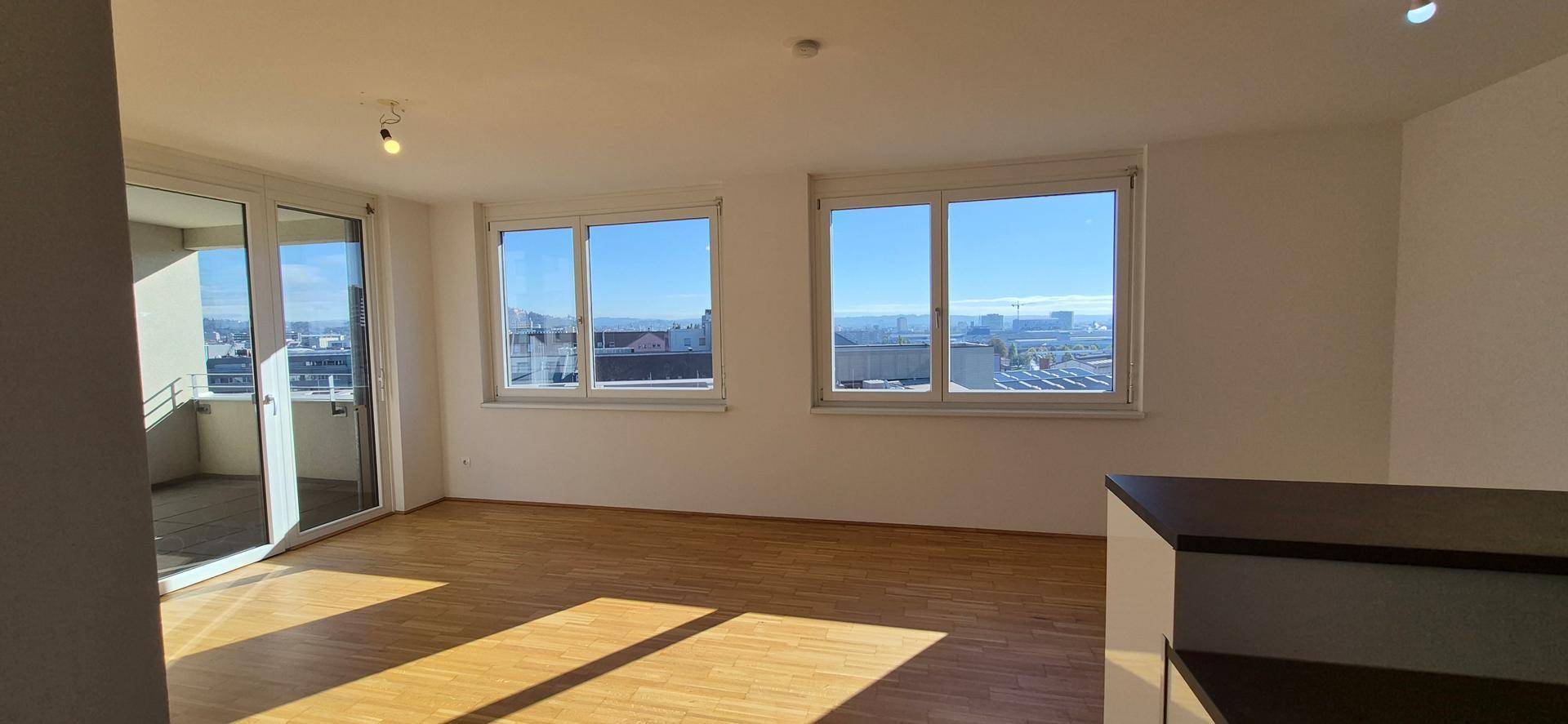 Lichtdurchfluteter Wohnbereich mit Holzboden und weitem Blick über die Stadt.
