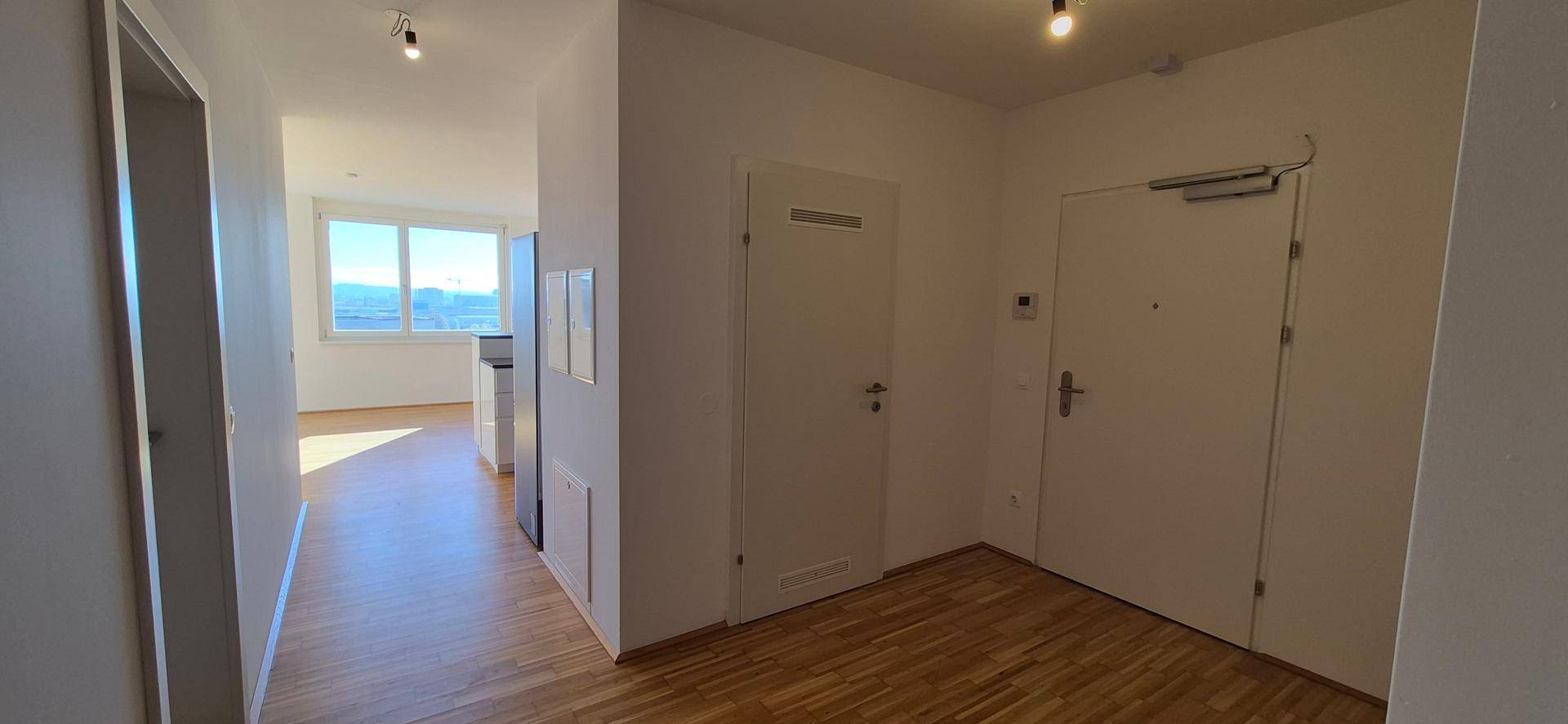 Heller Eingangsbereich mit Holzboden und Blick in den Wohnbereich.