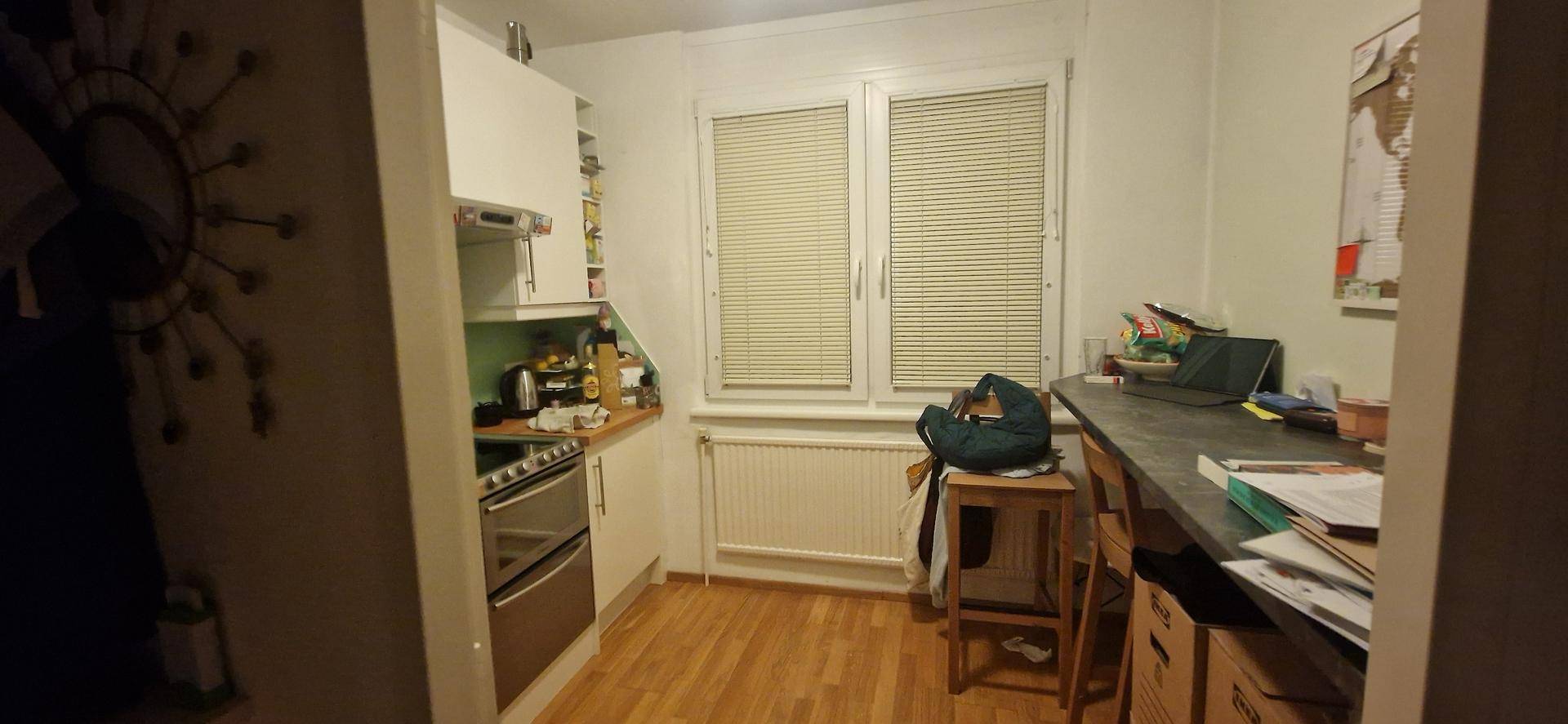 Kleine Küche mit weißen Schränken, Herd und einem Arbeitsbereich mit Fenster.