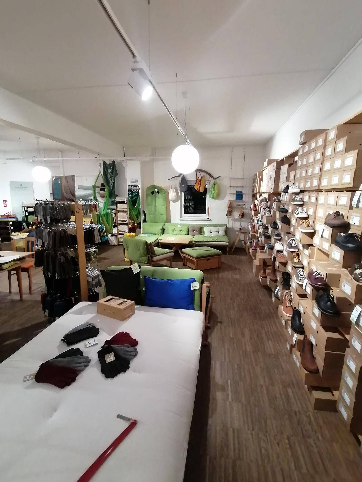 Blick in den Verkaufsraum mit einem grünen Sofa, einer Bettdarstellung und weiteren Schuhregalen.