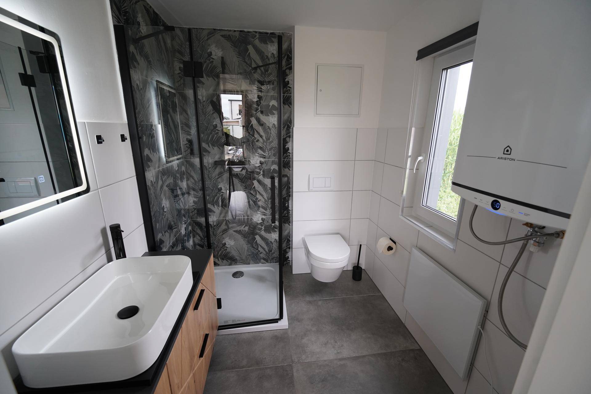Modernes Badezimmer mit begehbarer Dusche, Waschbecken und Fenster, inklusive Warmwasserbereiter.