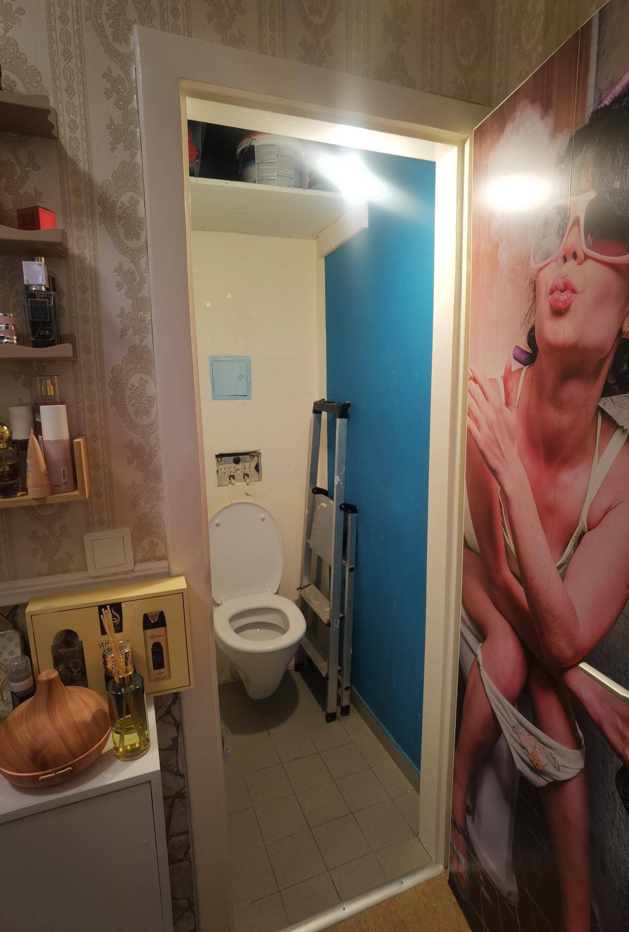 Separate Toilette mit Wand-WC und Fliesenboden, akzentuiert durch eine blaue Wand.