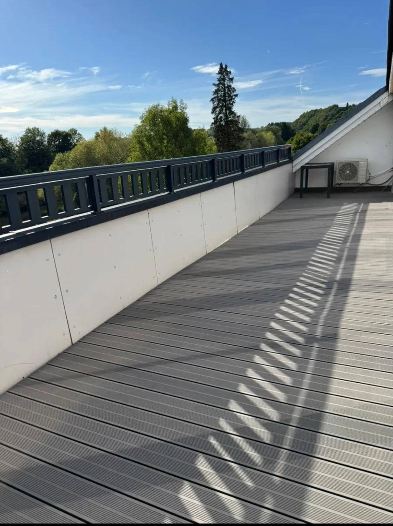 Weitläufige Terrasse mit Blick ins Grüne, ausgestattet mit einer Klimaanlage und modernen Bodenbelägen.