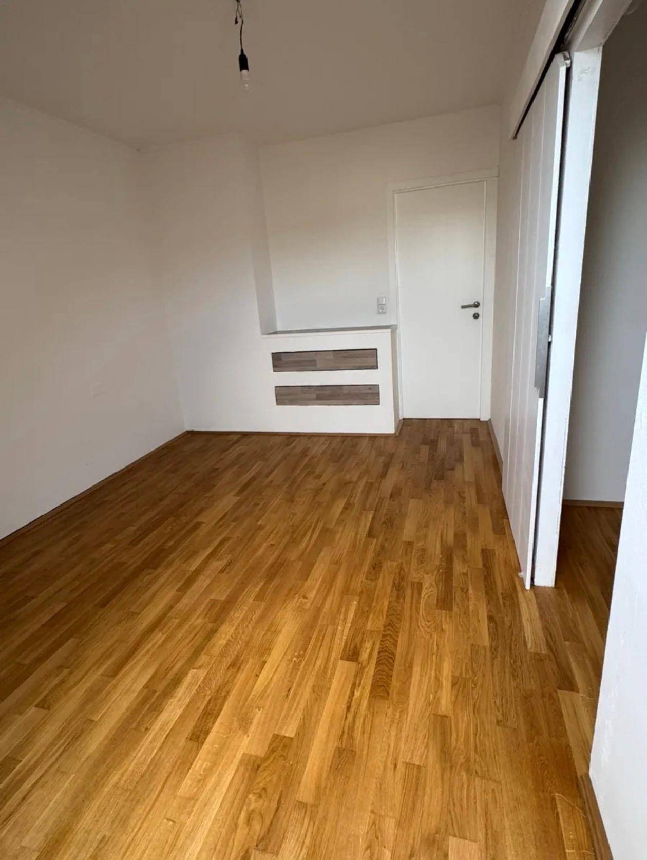 Geräumiges Schlafzimmer mit Parkettboden, weißen Wänden und einer praktischen Nische.