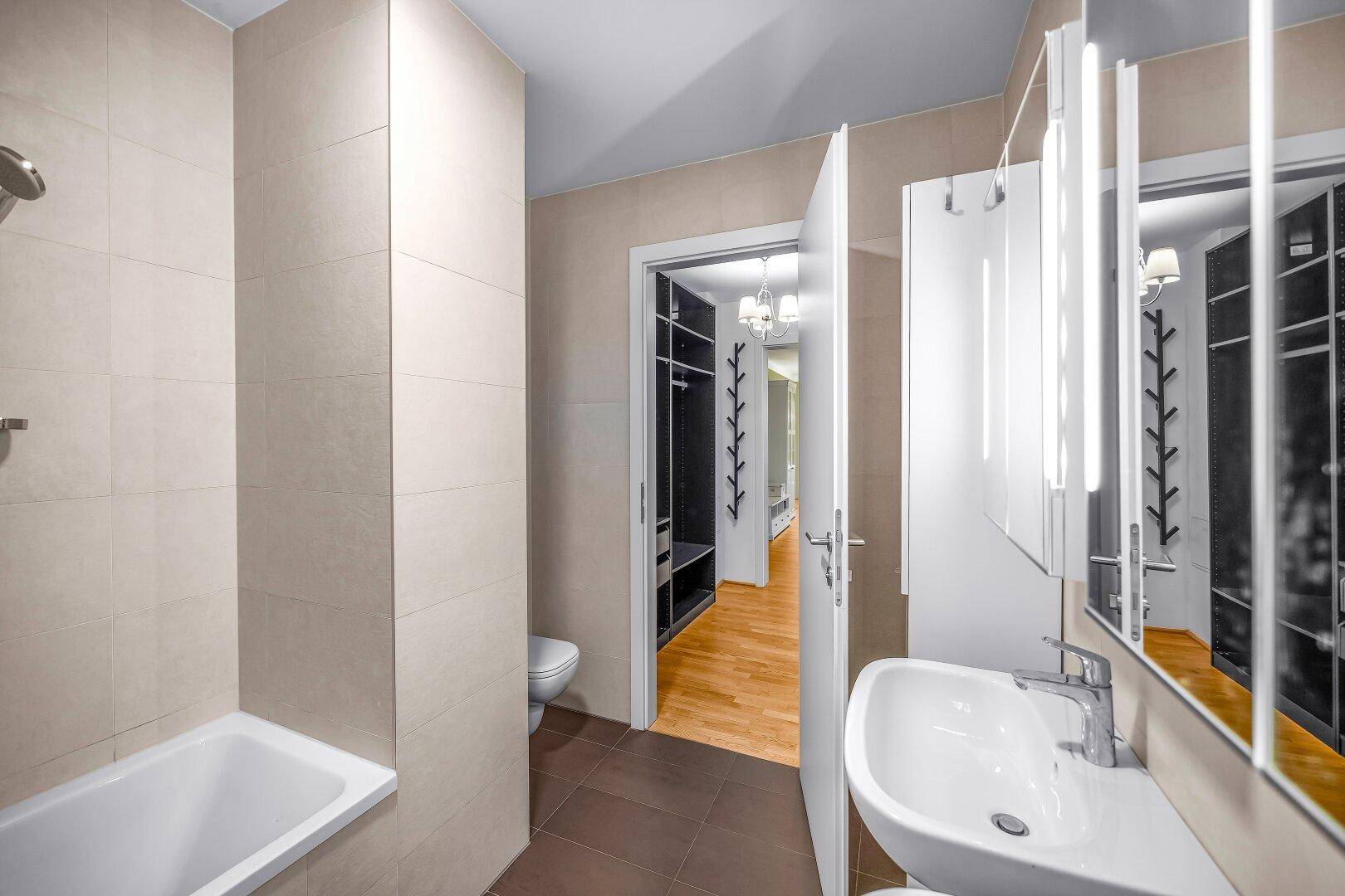 Modernes Badezimmer mit Badewanne, Waschbecken und hellen Fliesen.