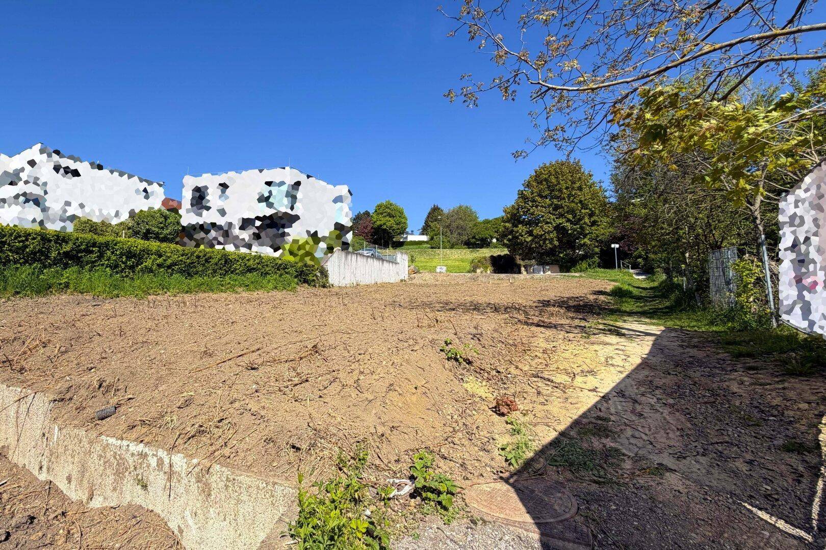 Freigelegtes Baugrundstück mit Erdboden und Blick auf die umliegende Bebauung.