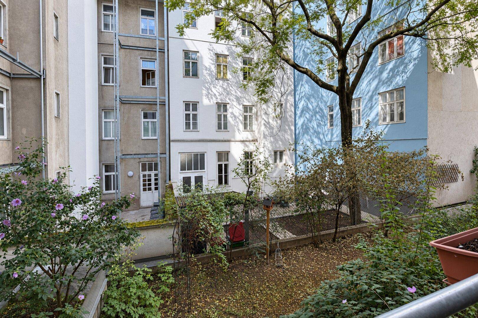 Blick auf den begrünten Innenhof mit Bäumen und umliegenden Gebäuden.