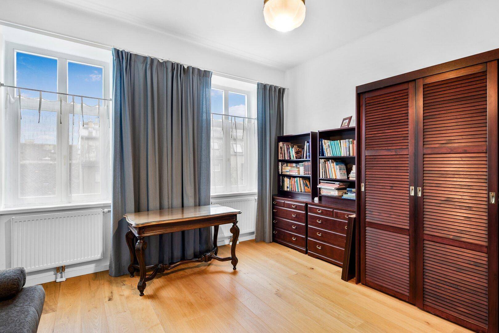 Arbeitszimmer mit Holzboden, Schreibtisch, Bücherregalen und großem Kleiderschrank.