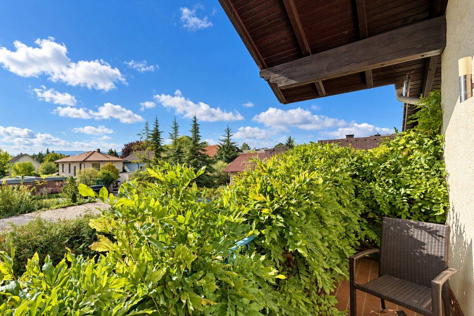 Kleiner Balkon mit üppiger Bepflanzung und weitem Blick über die umliegende Nachbarschaft.
