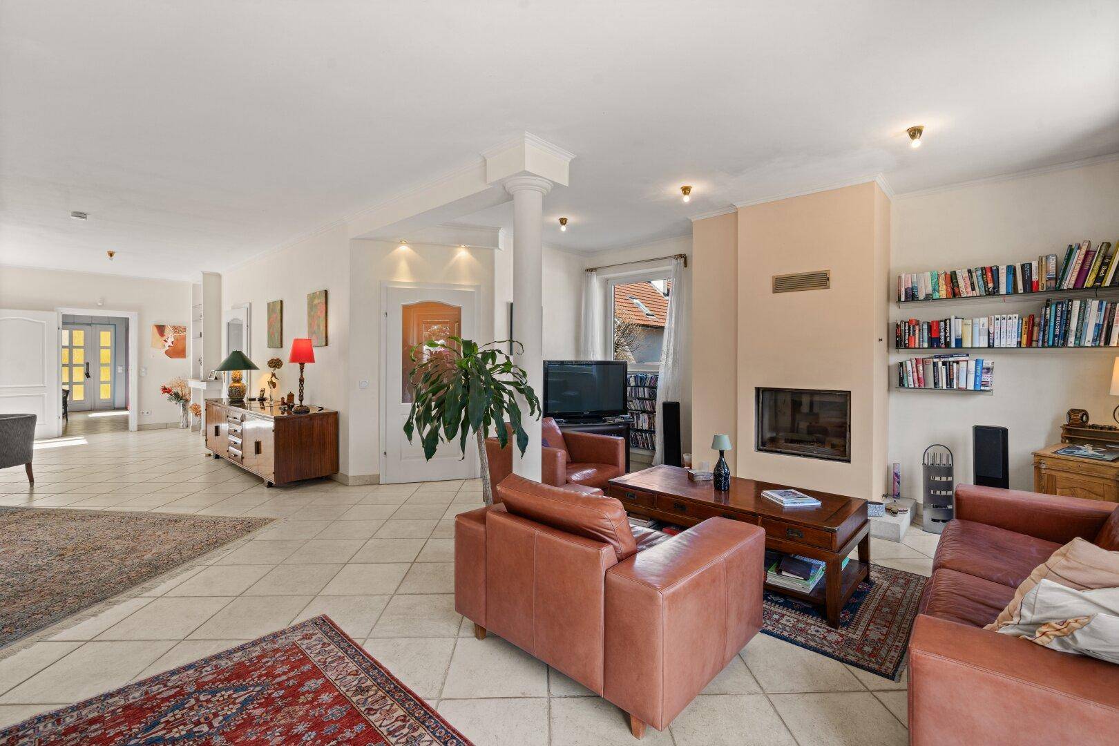 Geräumiger Wohnbereich mit Kamin, Fliesenboden und Ledersofas, ideal zum Entspannen.