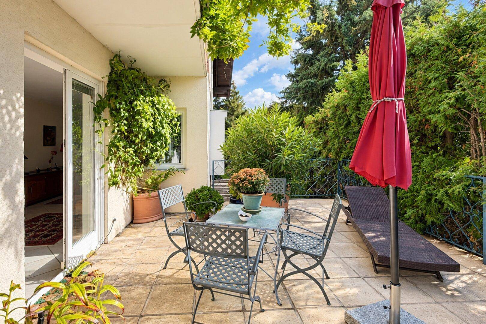 Gemütliche Terrasse mit Sitzgelegenheiten, Sonnenschirm und üppiger Begrünung.