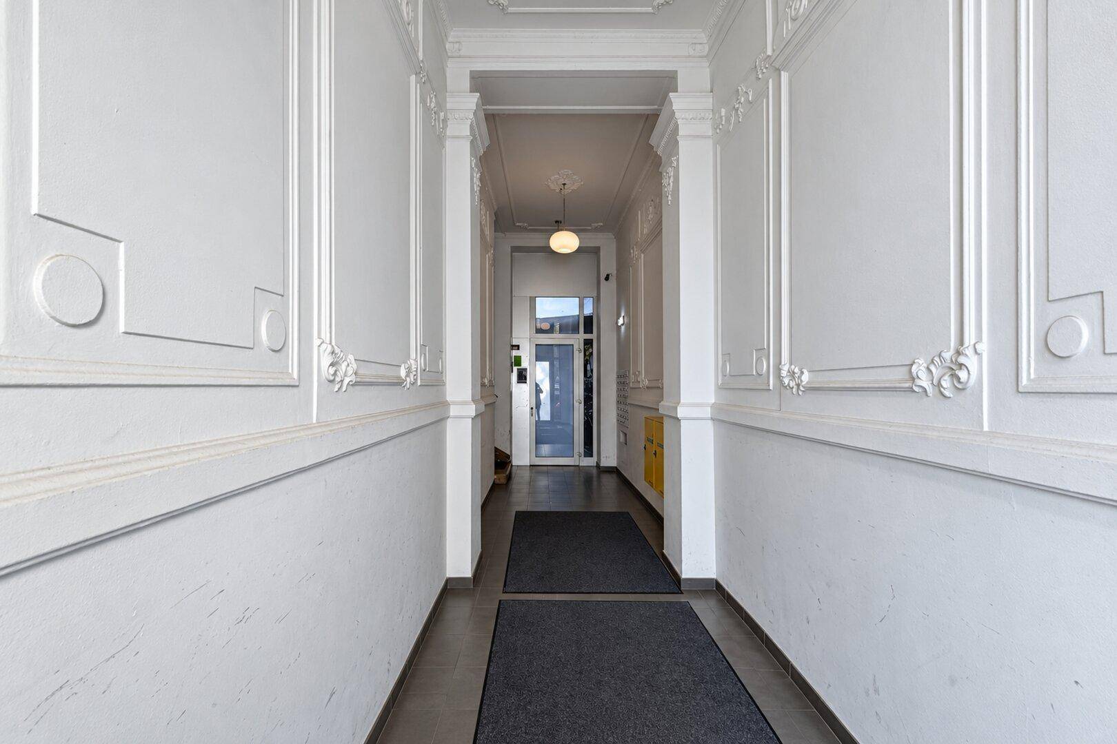 Repräsentativer Eingangsbereich mit aufwendigen Wandverkleidungen und Stuckelementen an der Decke.