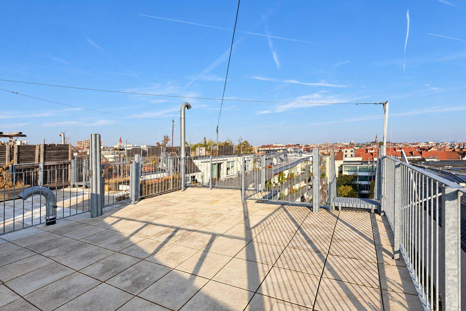 Weitläufige Dachterrasse mit Fliesenboden und Panoramablick über die städtische Umgebung.
