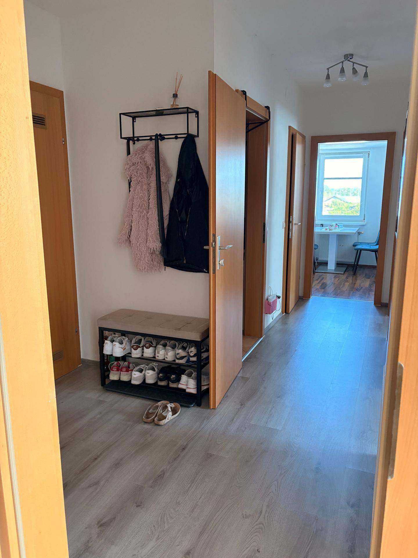 Heller Flur mit praktischer Garderobe, Schuhregal und Zugang zu verschiedenen Zimmern.