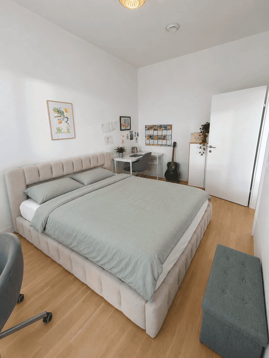 Helles Schlafzimmer mit großem Bett, Schreibtisch und hellem Holzfußboden.