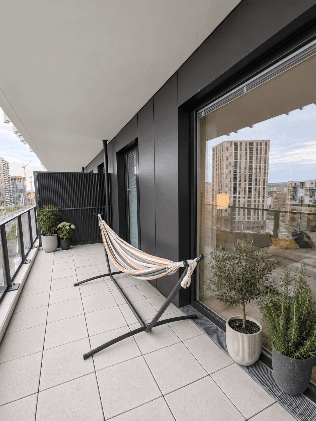 Balkon mit Hängematte und Pflanzen, bietet einen Blick auf die umliegenden Gebäude.
