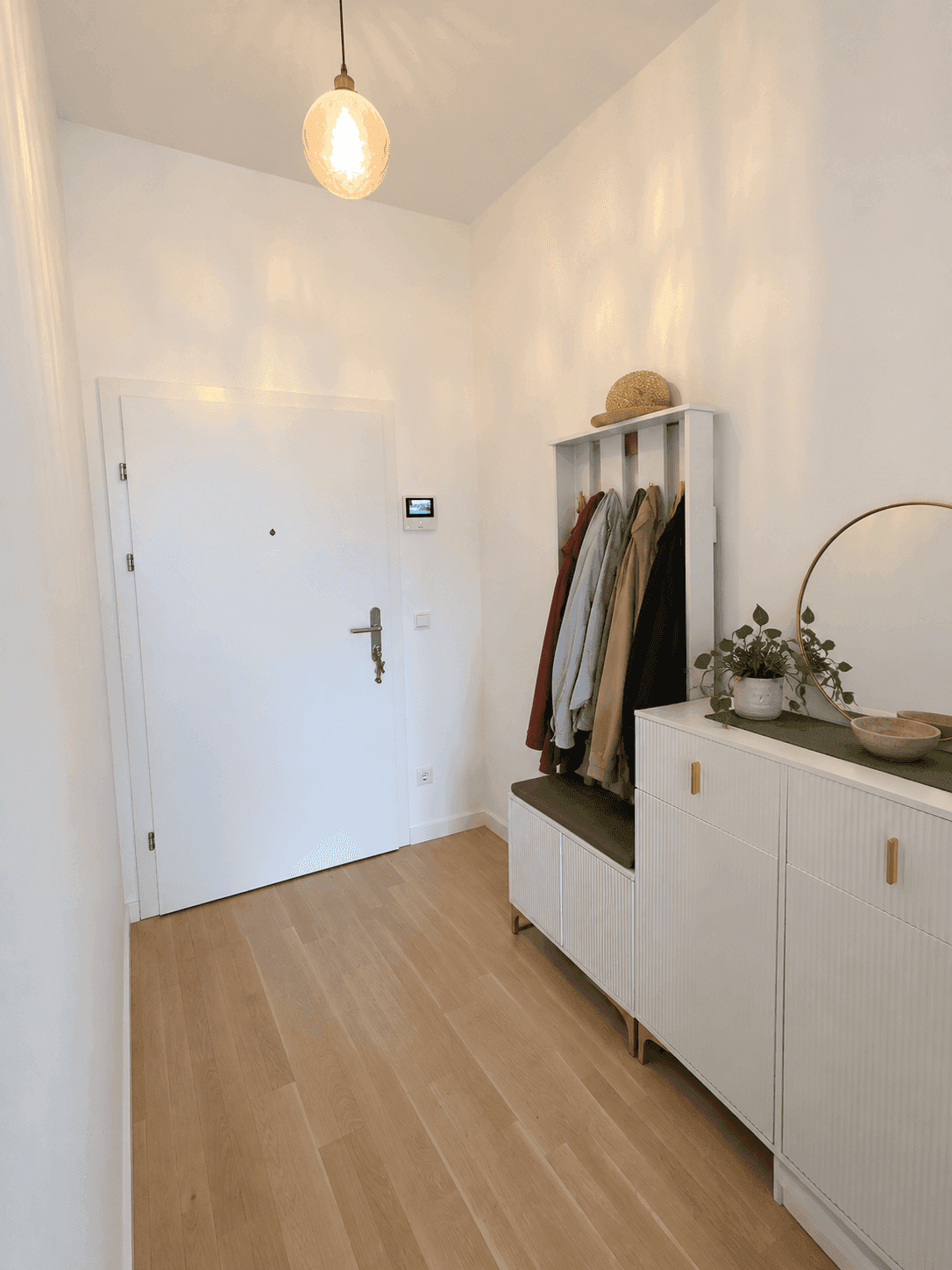 Heller Eingangsbereich mit Garderobe, Schuhschrank und Holzfußboden.