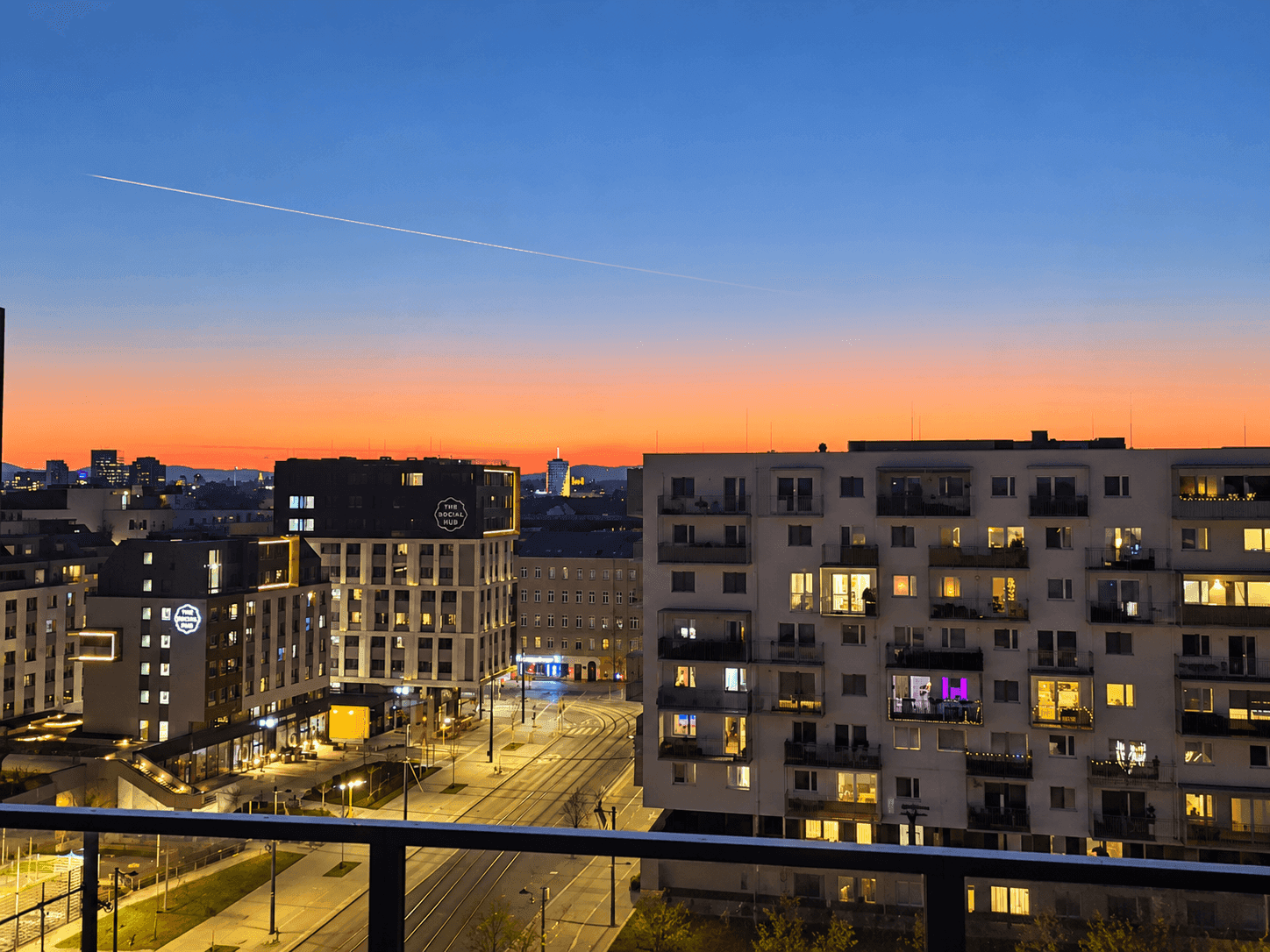 Panoramablick auf die Stadt bei Sonnenuntergang mit beleuchteten Gebäuden und Straßen.