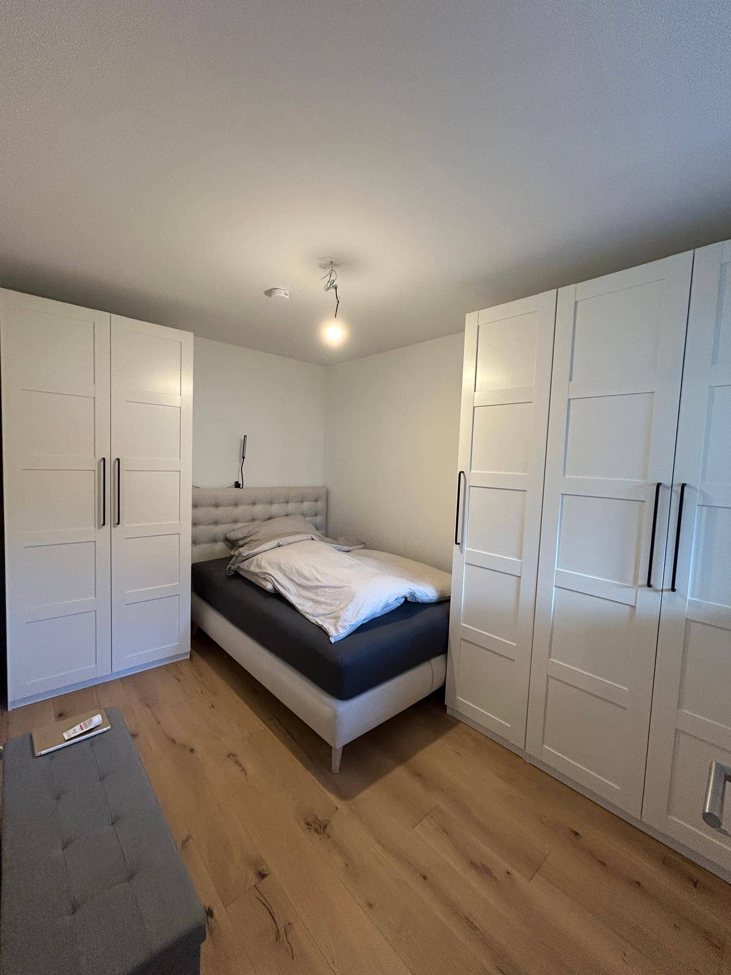 Schlafzimmer mit Doppelbett, Einbauschränken und hellem Holzboden.