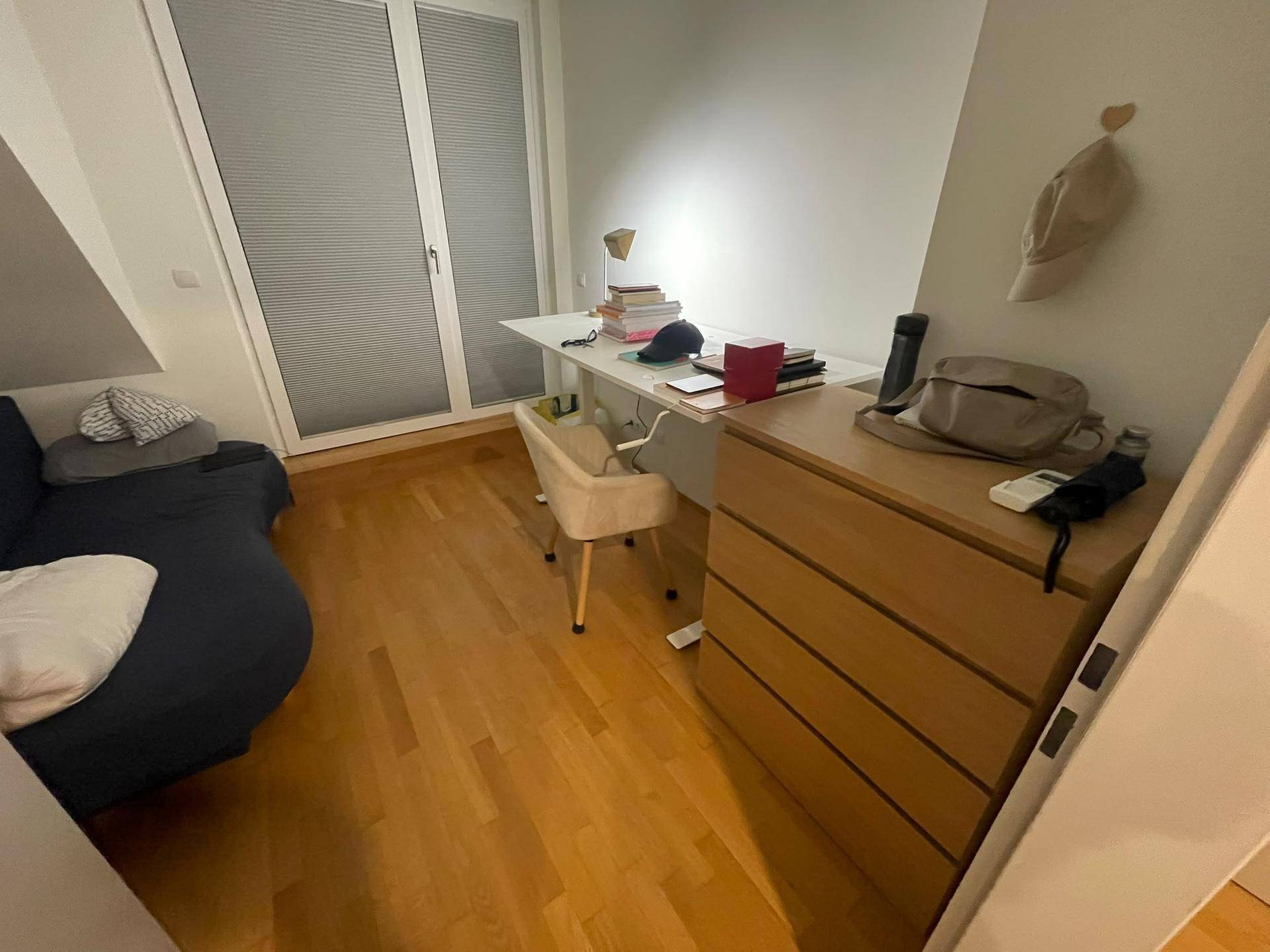 Funktionales Dachzimmer mit Schreibtisch, Kommode und Sofa, ideal für Arbeit und Entspannung.