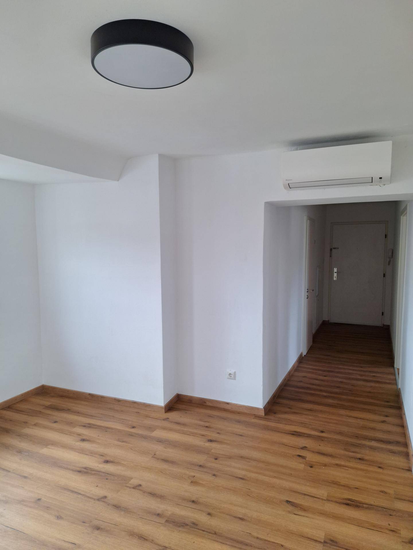 Heller Wohnbereich mit Laminatboden und Klimaanlage, der in einen Flur übergeht und viel Platz bietet.