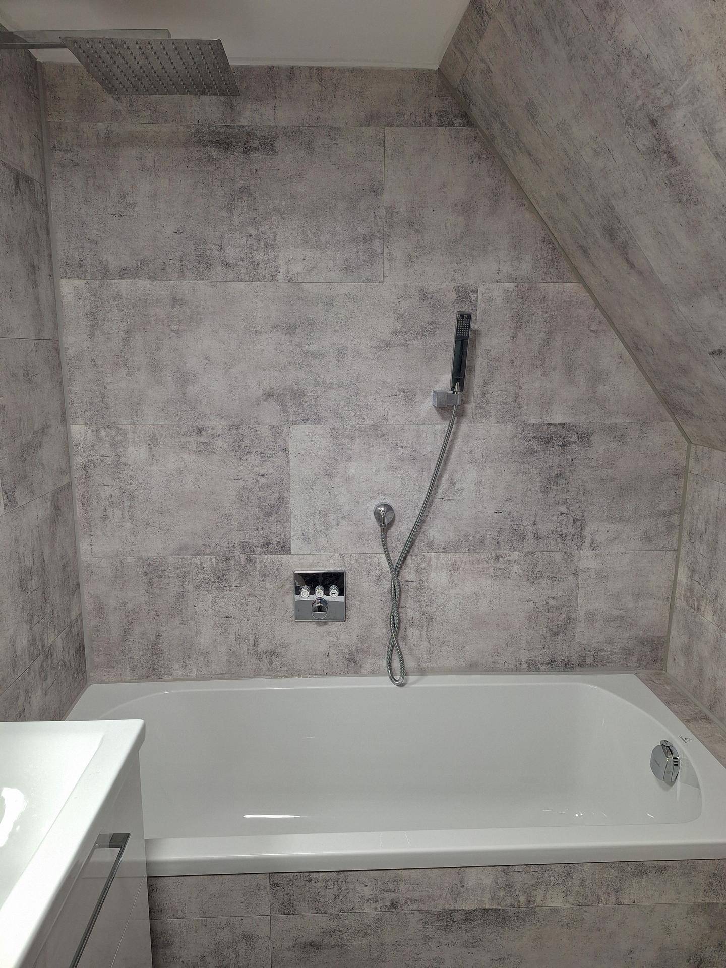 Badewanne mit moderner Regendusche und Handbrause in einem gefliesten Badezimmer im Dachgeschoss, stilvoll gestaltet.
