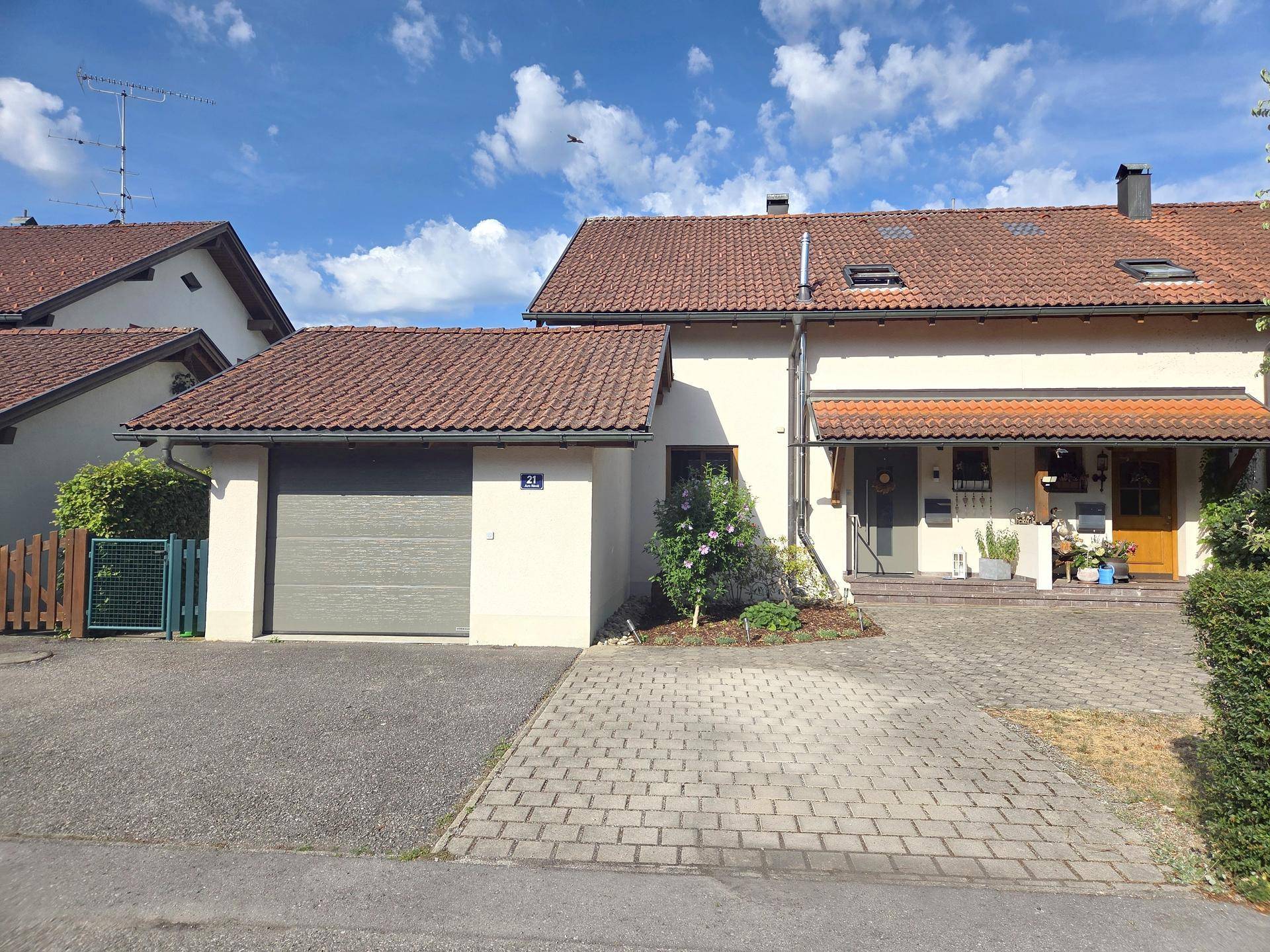 Vorderansicht des Hauses mit integrierter Garage, gepflasterter Einfahrt und Vorgarten.