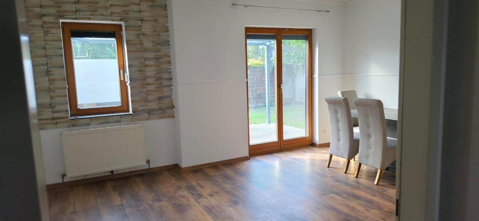 Heller Essbereich mit Laminatboden, weiß gestrichenen Wänden und Zugang zur Terrasse.