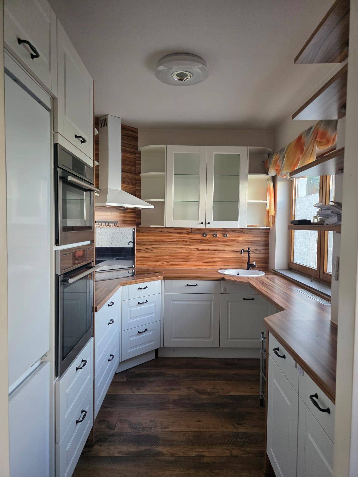 Moderne Küche mit weißen Schränken, Holz-Arbeitsplatten und integrierten Geräten.