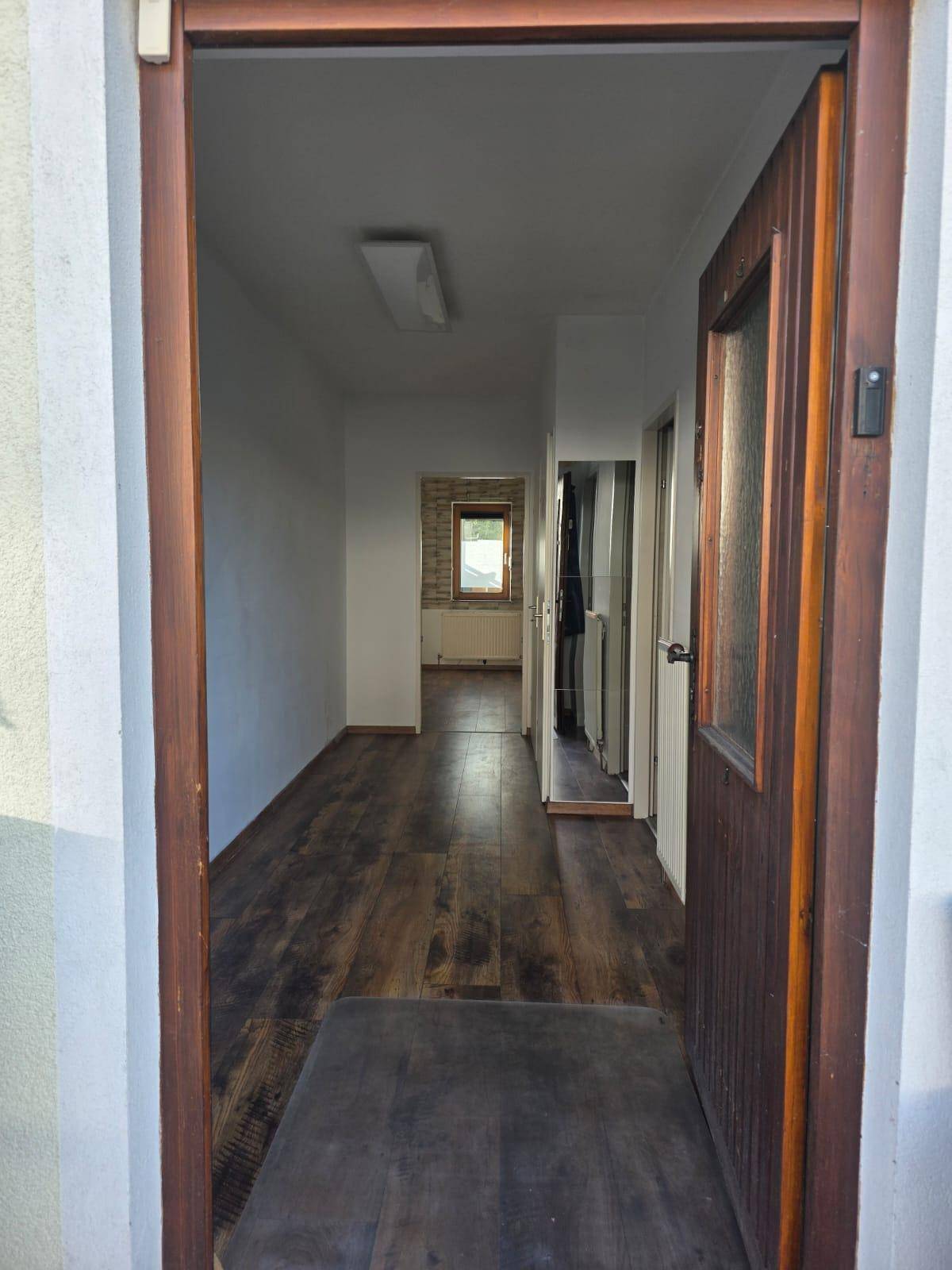 Eingangsbereich mit Laminatboden, der in einen hellen Flur und weitere Räume führt.