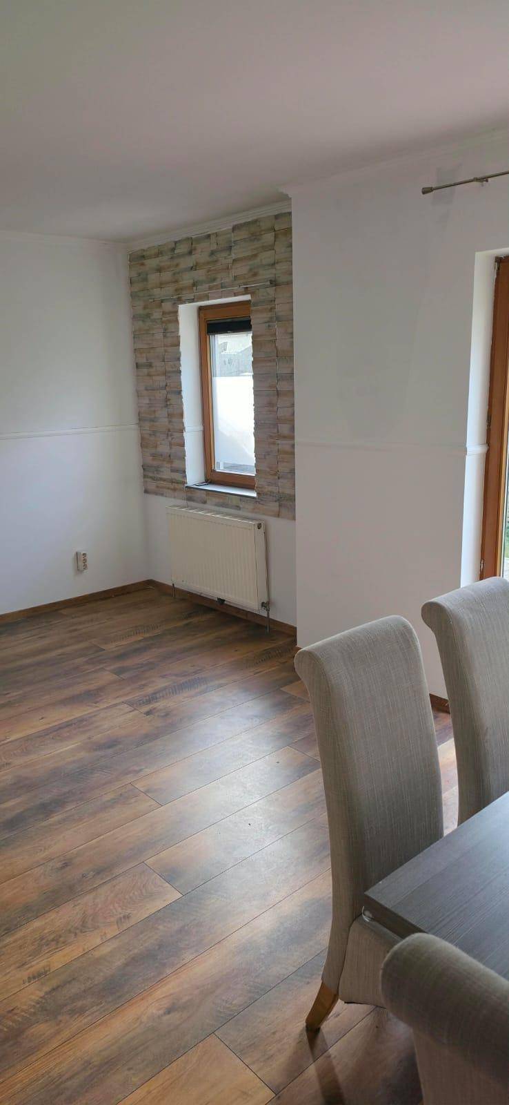 Essbereich mit dekorativer Steinwand, Laminatboden und einem Fenster, das viel Licht hereinlässt.